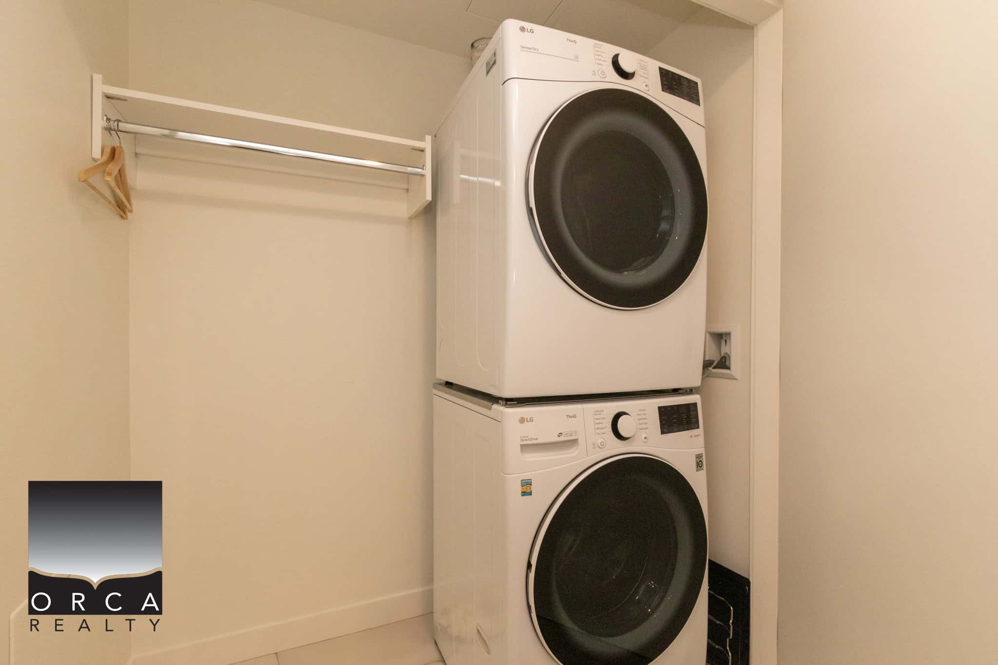 Modern front-loading washer and dryer set in a compact laundry closet with a built-in rod for hanging clothes. Perfect for small Vancouver Island homes or condos.