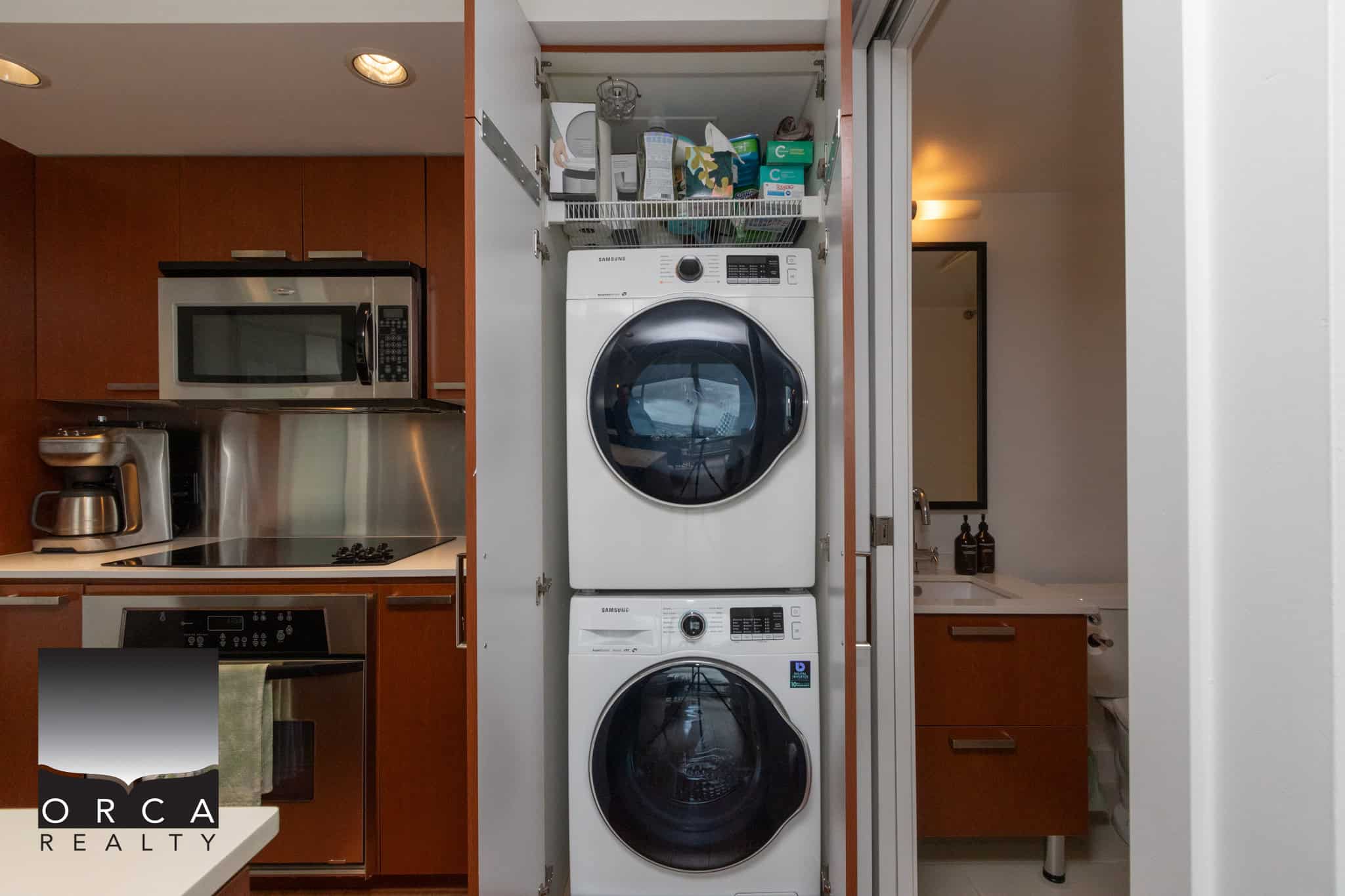 Efficient laundry closet with stacked washer and dryer units in a modern condo, featuring accessible storage and a sleek design to maximize space and functionality.