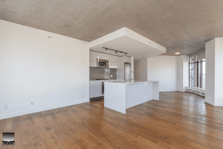 Modern open-concept kitchen in a contemporary Vancouver apartment, featuring hardwood flooring, large windows, and minimalist design, perfect for real estate listings and property showcases.
