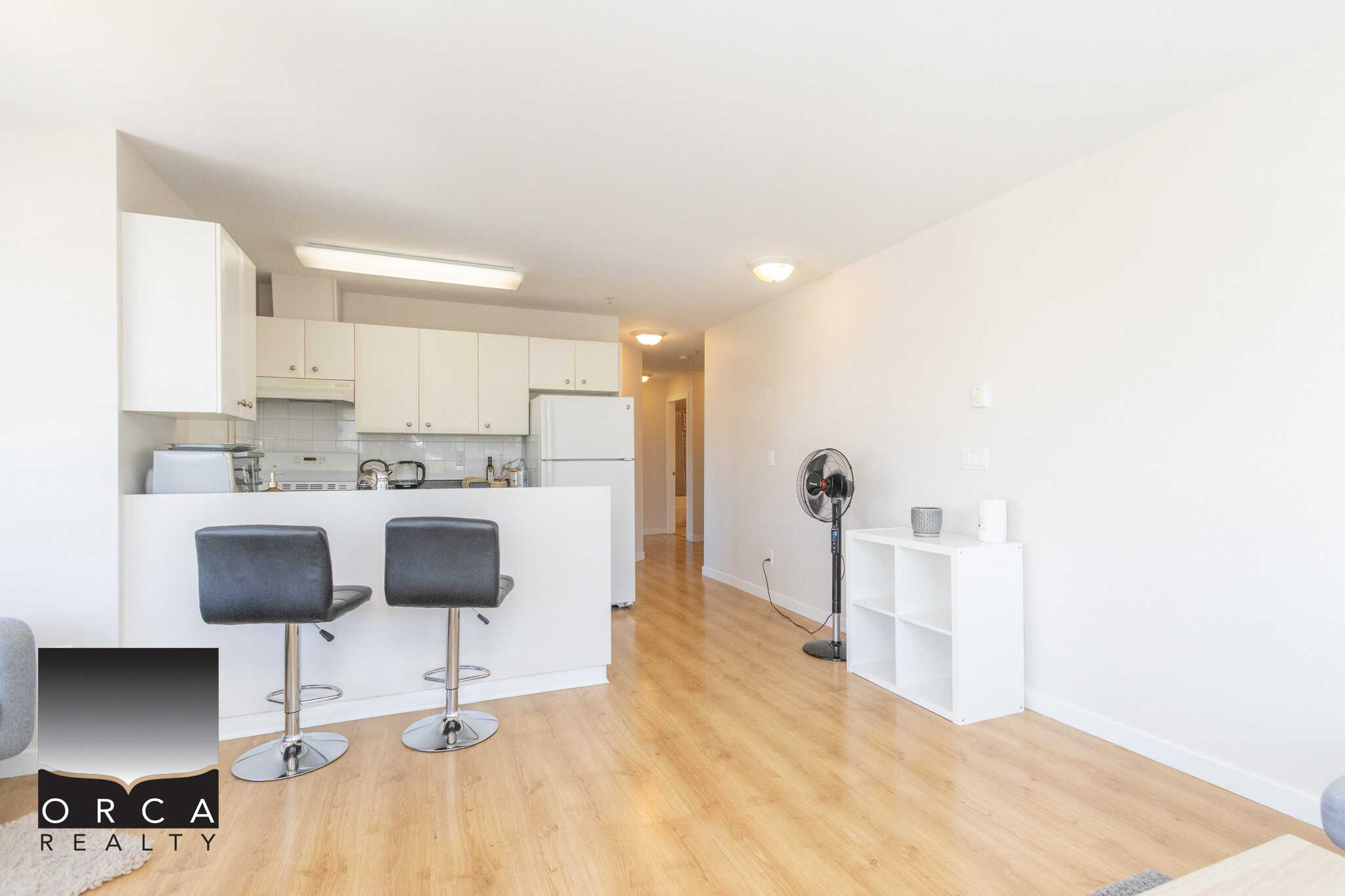 Bright, modern apartment interior with open-concept kitchen, white cabinetry, and minimalist decor. Ideal for Vancouver and Victoria real estate listings, emphasizing sleek design and natural light.