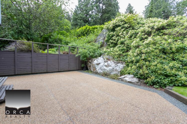 Spacious backyard patio with landscaped greenery and rock features, perfect for outdoor living and relaxation.