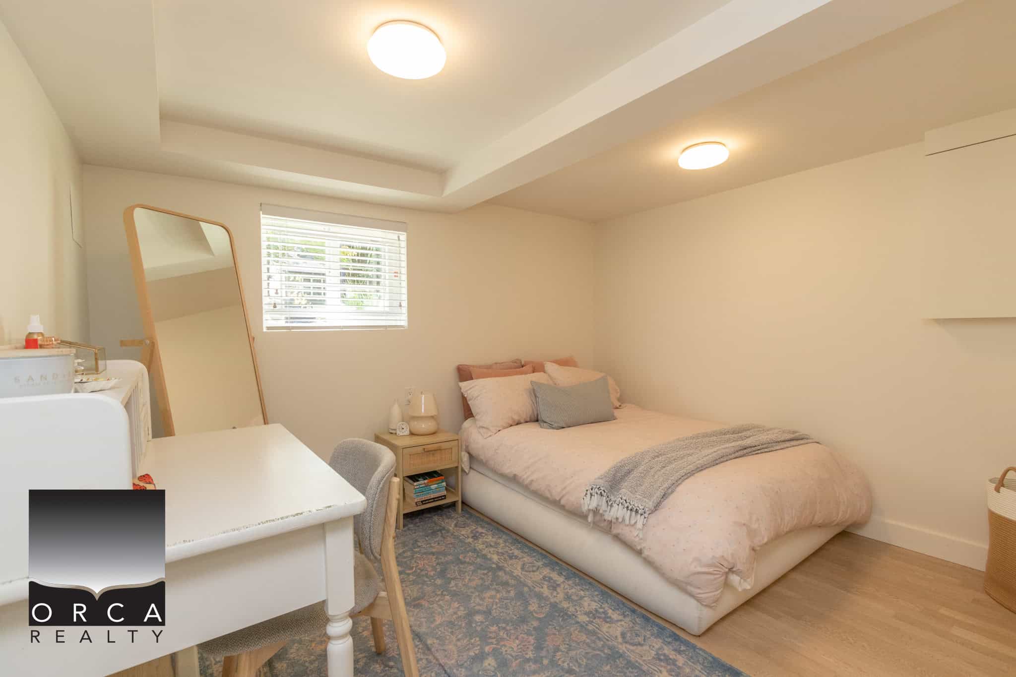 16 Bright bedroom with minimal decor, large window with white blinds, soft beige bedding, and hardwood flooring, showcasing a cozy, modern interior ideal for real estate listings on Orca Realty Inc. website.