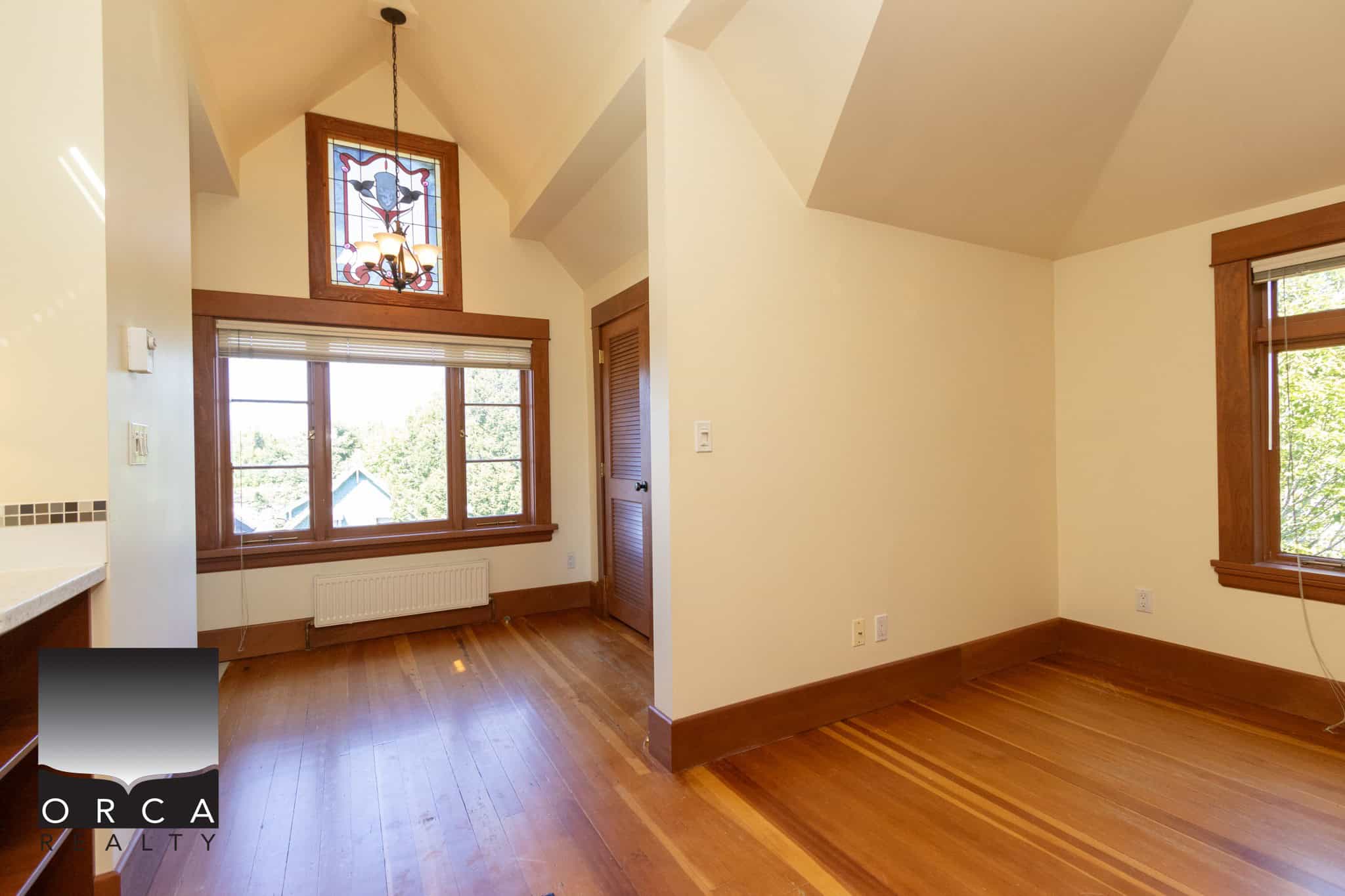 Bright sunny room with large windows and hardwood flooring, ideal for comfortable living or working spaces, showcasing quality home interior featuring classic wooden trim details.
