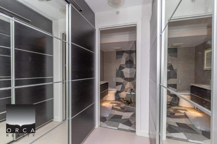 Modern bathroom with stylish geometric wall tiles and contemporary fixtures, featuring a spacious walk-in closet with mirrored sliding doors, perfect for luxury home living in Vancouver.