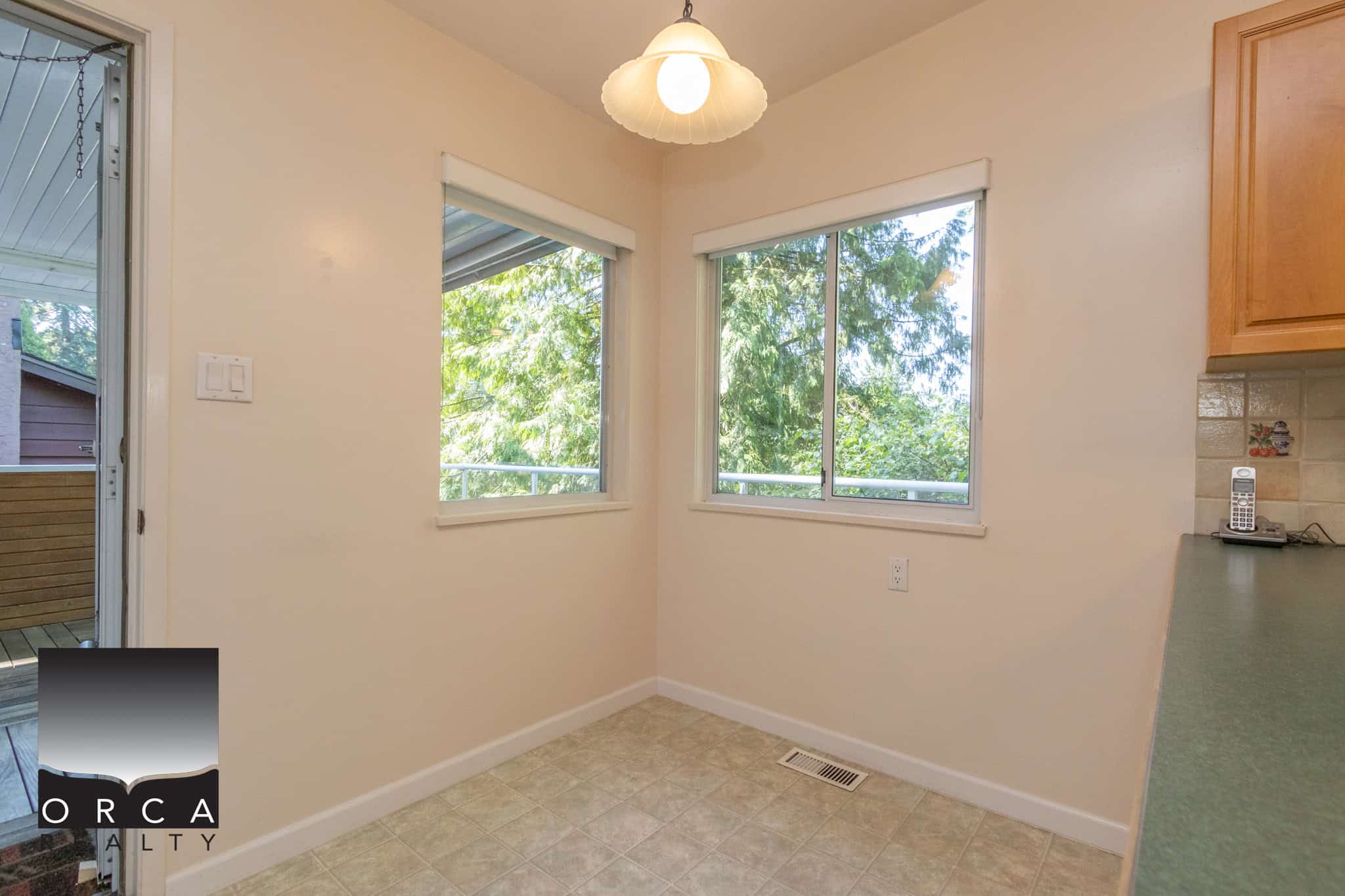 Bright kitchen or dining area with large windows showcasing lush greenery, ample natural light, and a cozy atmosphere, ideal for family meals and entertaining.