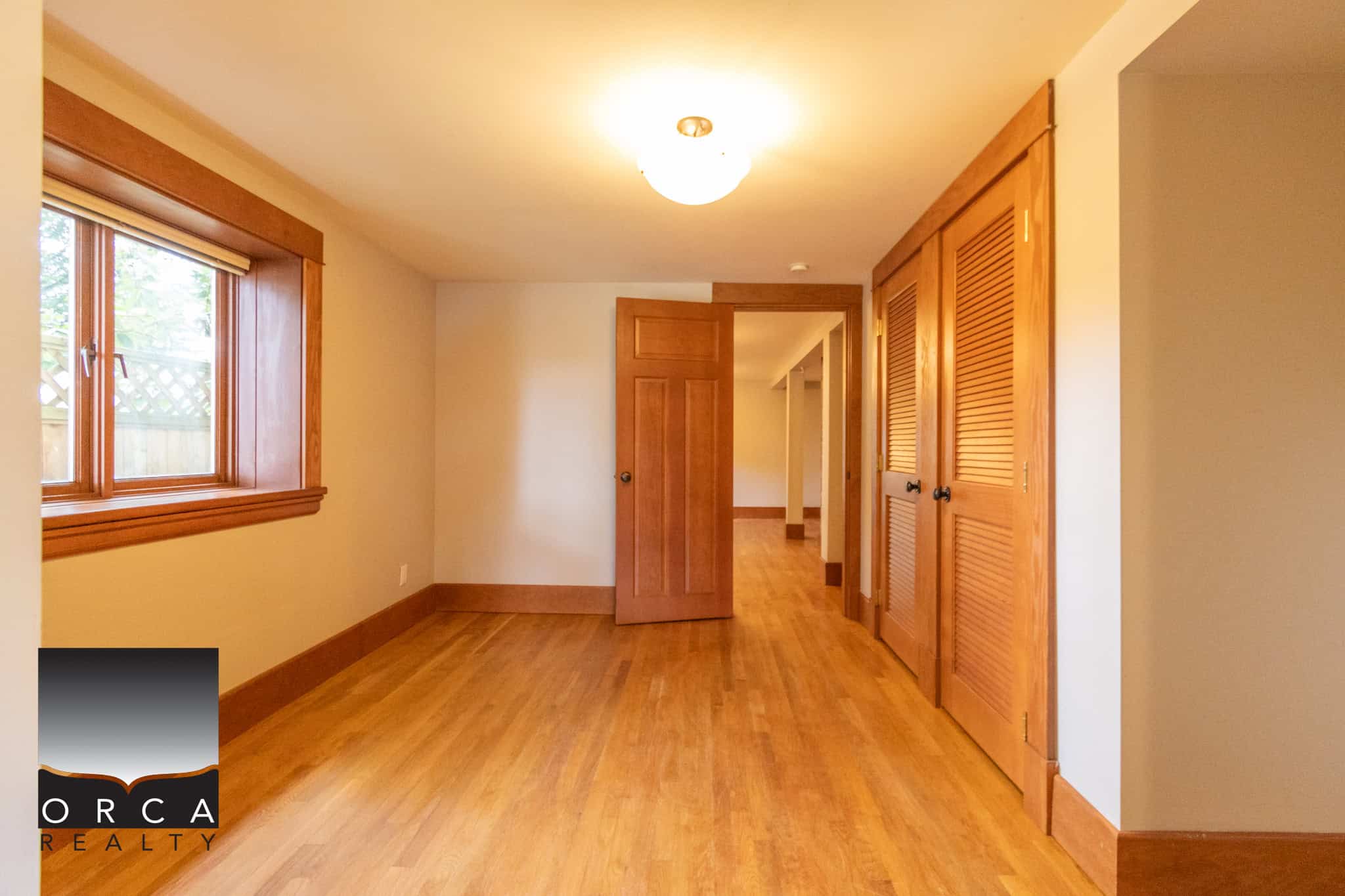 Bright hardwood flooring and natural wood window trim in a cozy bedroom with closet space, ideal for homebuyers seeking timeless, warm interior design in Vancouver homes.