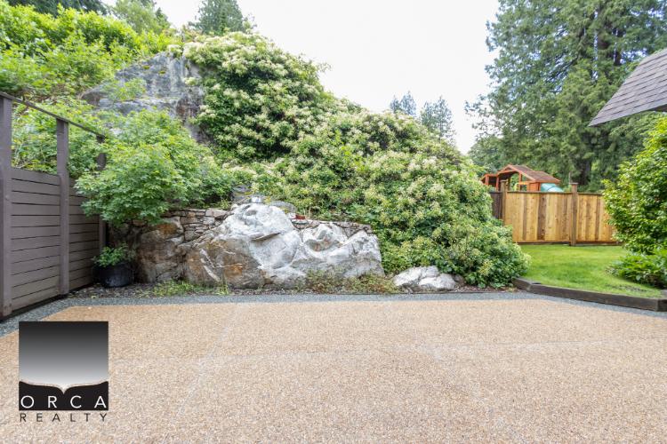 Lush backyard garden with rocks, trees, and a wooden fence, perfect for outdoor living and relaxation in Vancouver.
