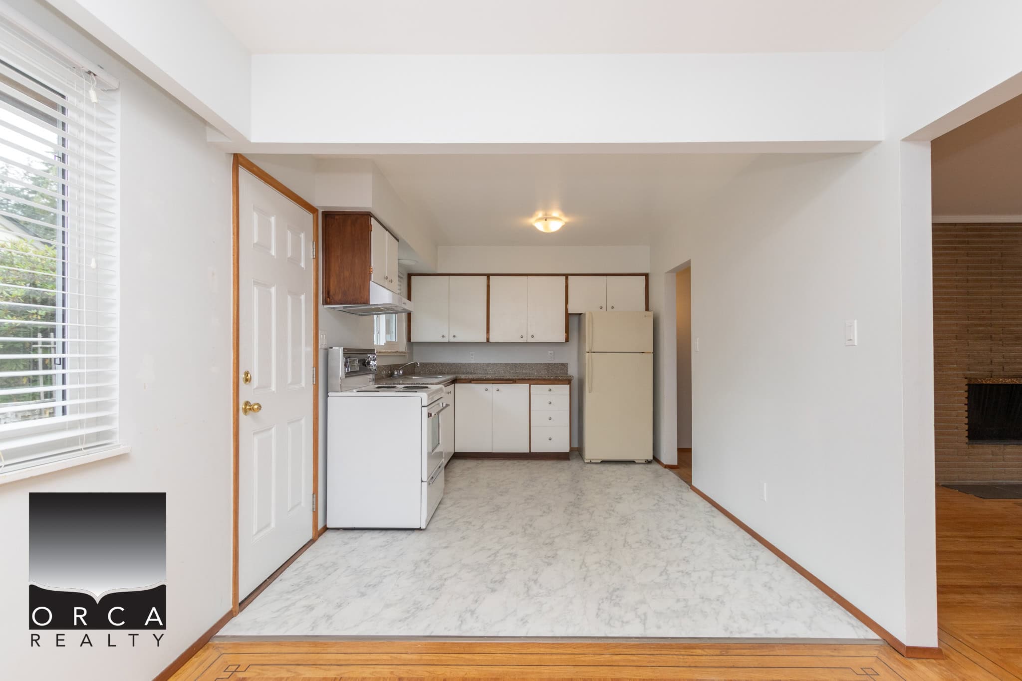 17 Bright kitchen with white cabinets, refrigerator, and stove, featuring a cozy open concept space with natural light and hardwood flooring, ideal for Vancouver Island real estate listings.