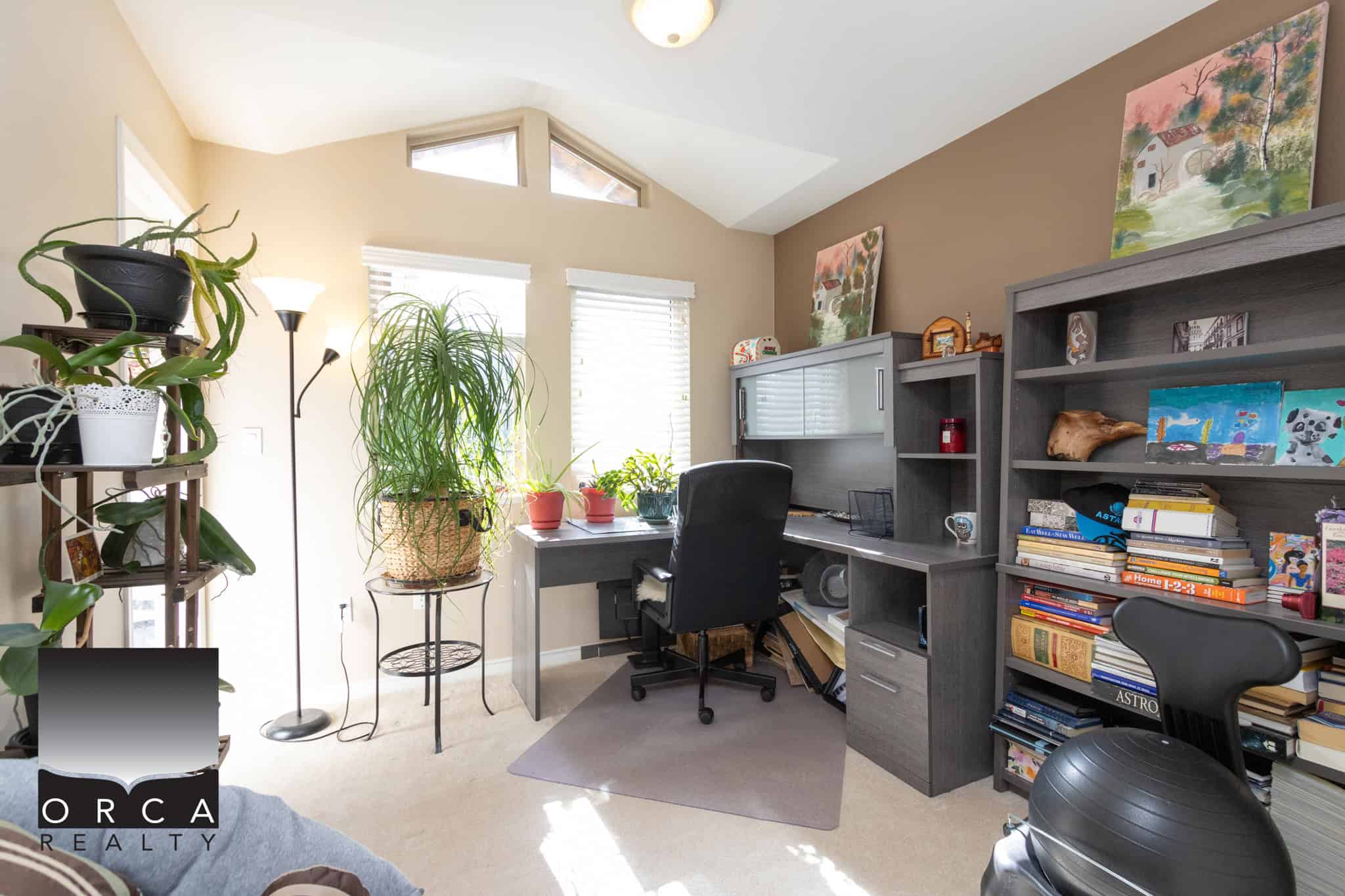 17 Lush home office with large windows, abundant natural light, and assorted plants and artwork, ideal for productivity and creativity.
