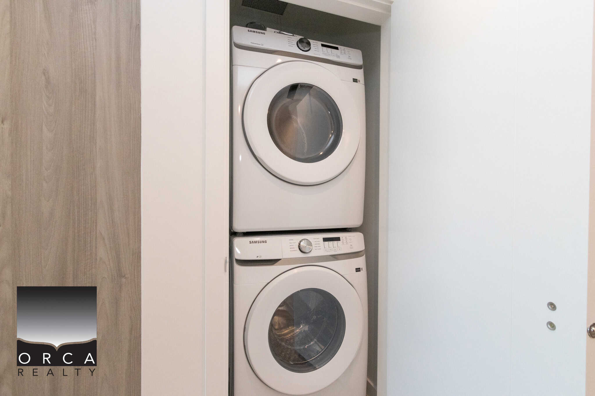 17 Efficient stacked washer and dryer inside a modern laundry closet, ideal for condo or apartment living, showcasing high-quality laundry appliances from Orca Realty Inc. in en_CA.