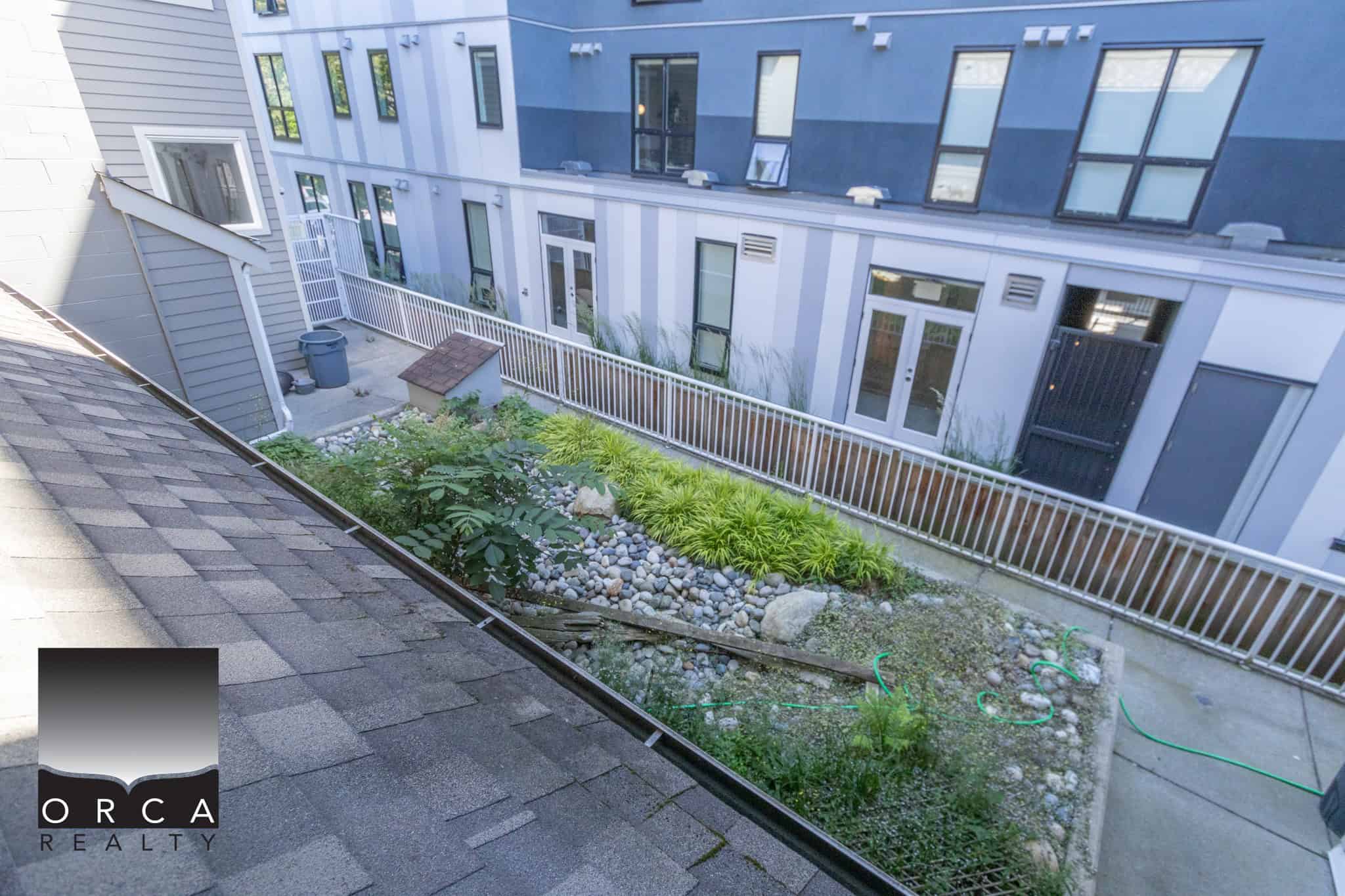 Bright private backyard with modern townhome units, lush landscaping, and a secure fenced patio area, offering ideal outdoor space for residents in Vancouver’s real estate market.