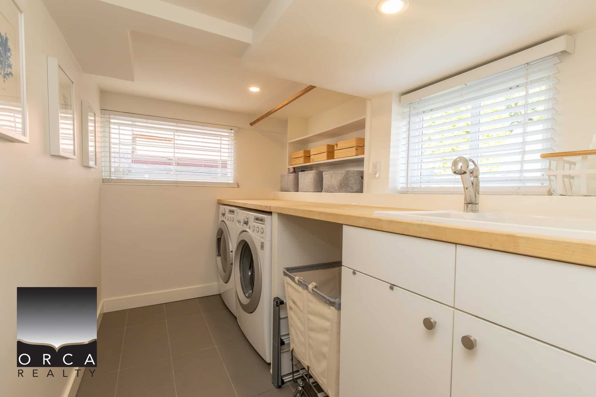 18 Bright laundry room with front-loading washer and dryer, white cabinetry, natural wood countertop, and ample window light, ideal for modern Vancouver homes.