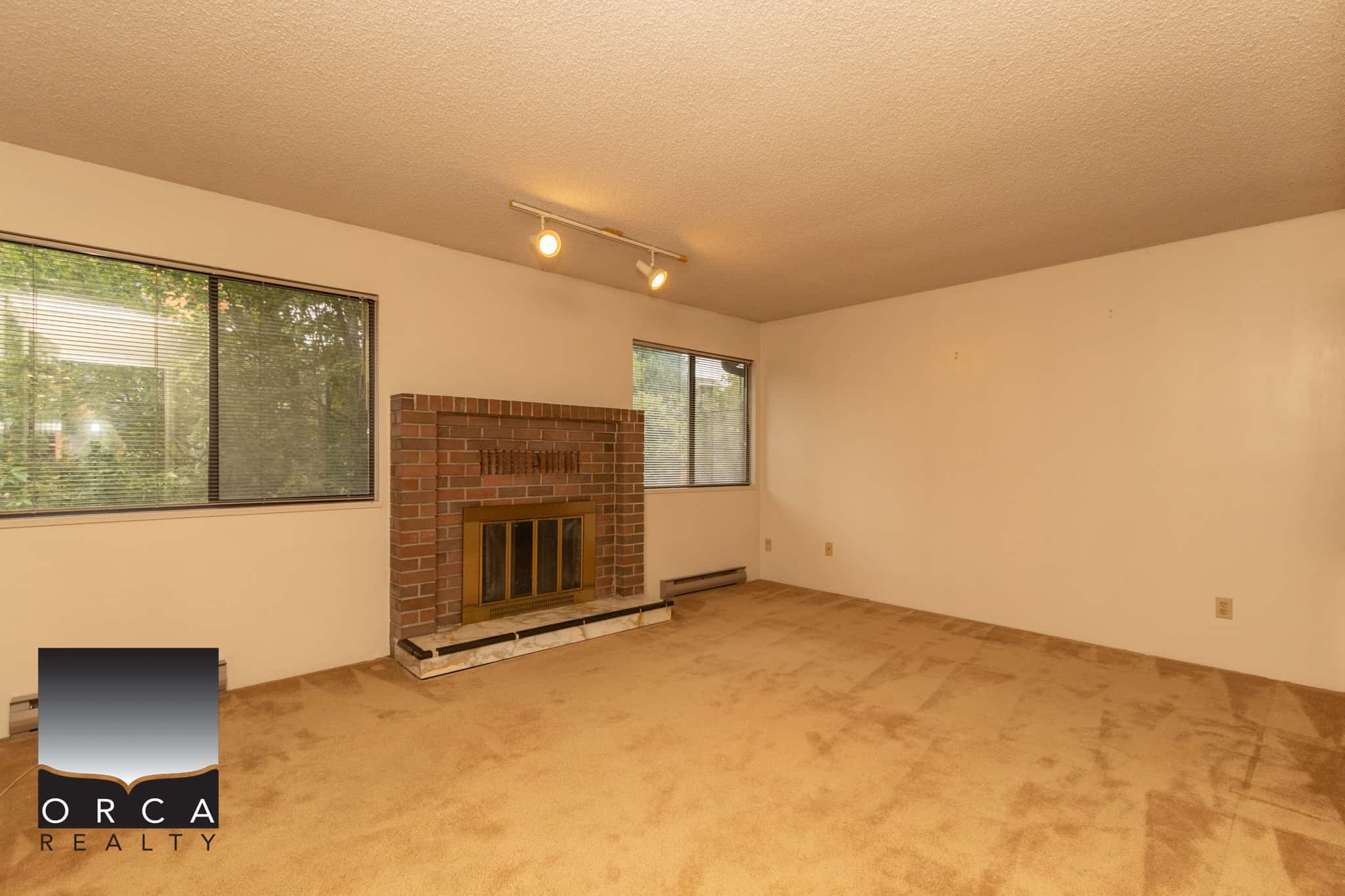 Bright living room with brick fireplace and large windows offering natural light in Vancouver area homes. Perfect space for relaxing and entertaining.