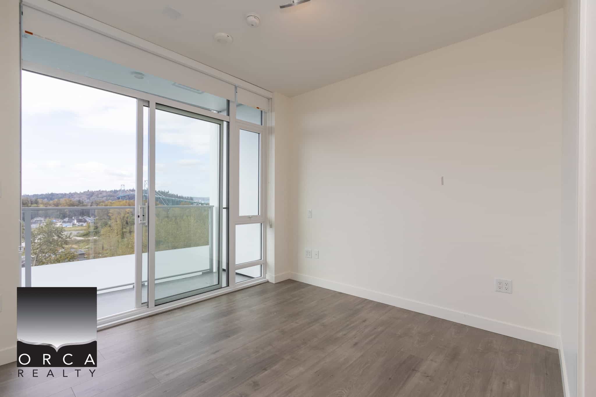 Bright modern apartment interior with large glass sliding doors leading to balcony, showcasing Vancouver views, ideal for real estate listings and property marketing.