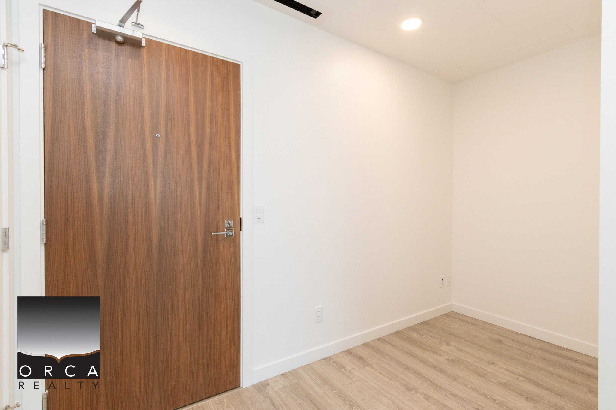 18 Bright modern interior with white walls and light wood flooring, featuring a sleek wooden door, ideal for Vancouver or BC real estate listings.