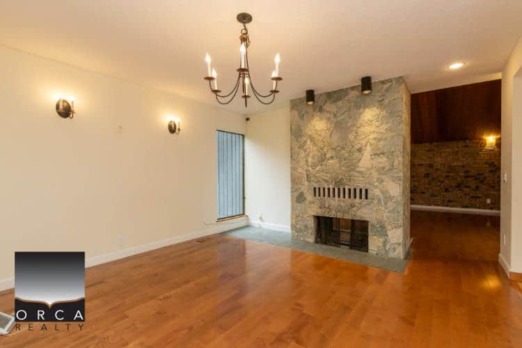 Modern living room with stone fireplace, hardwood floors, above-average lighting, and a cozy ambiance, ideal for homebuyers seeking comfort and style in their new residence.