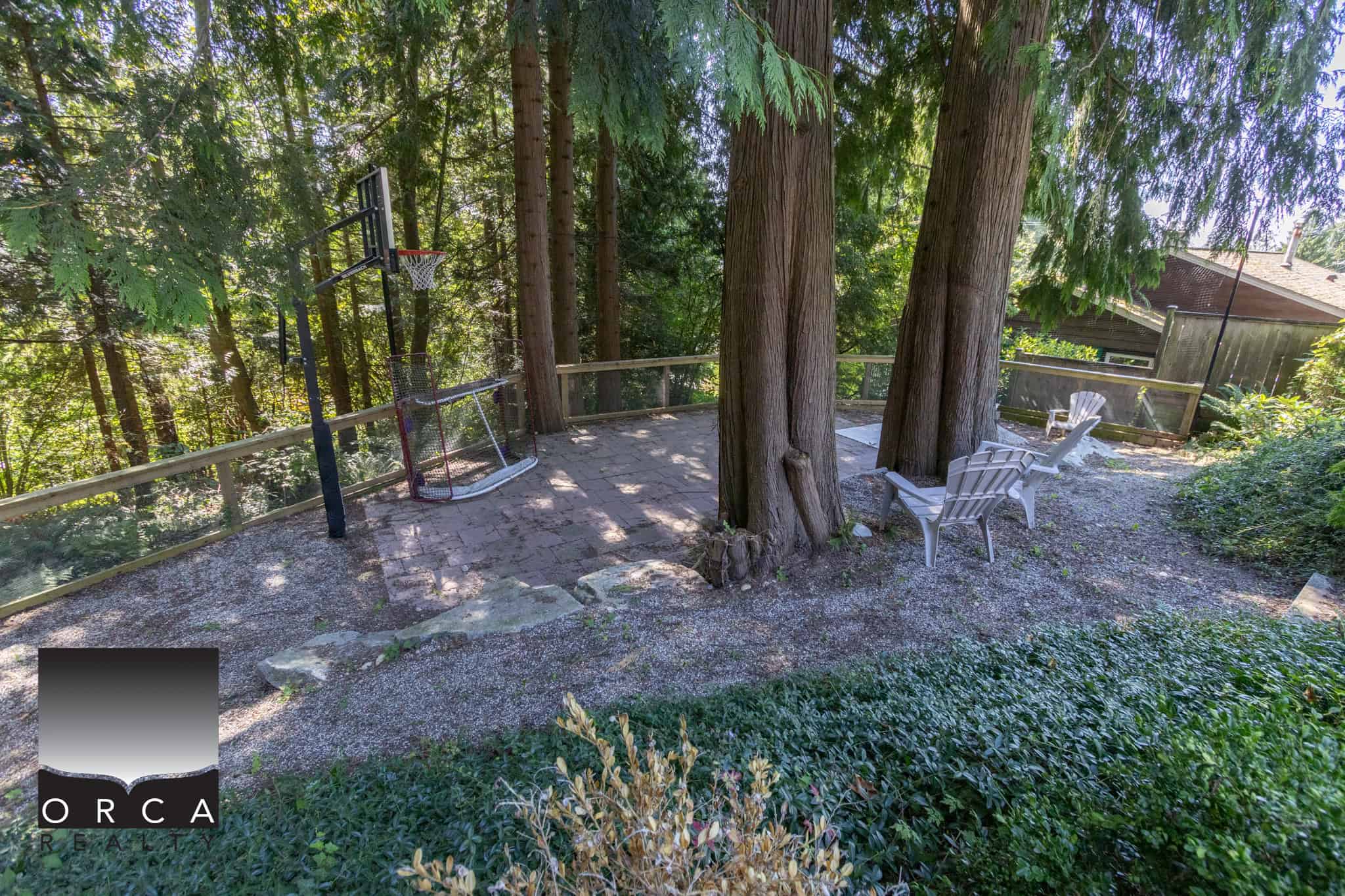 Secluded backyard featuring mature trees, cozy seating area, and natural surroundings, perfect for relaxation and outdoor activities.