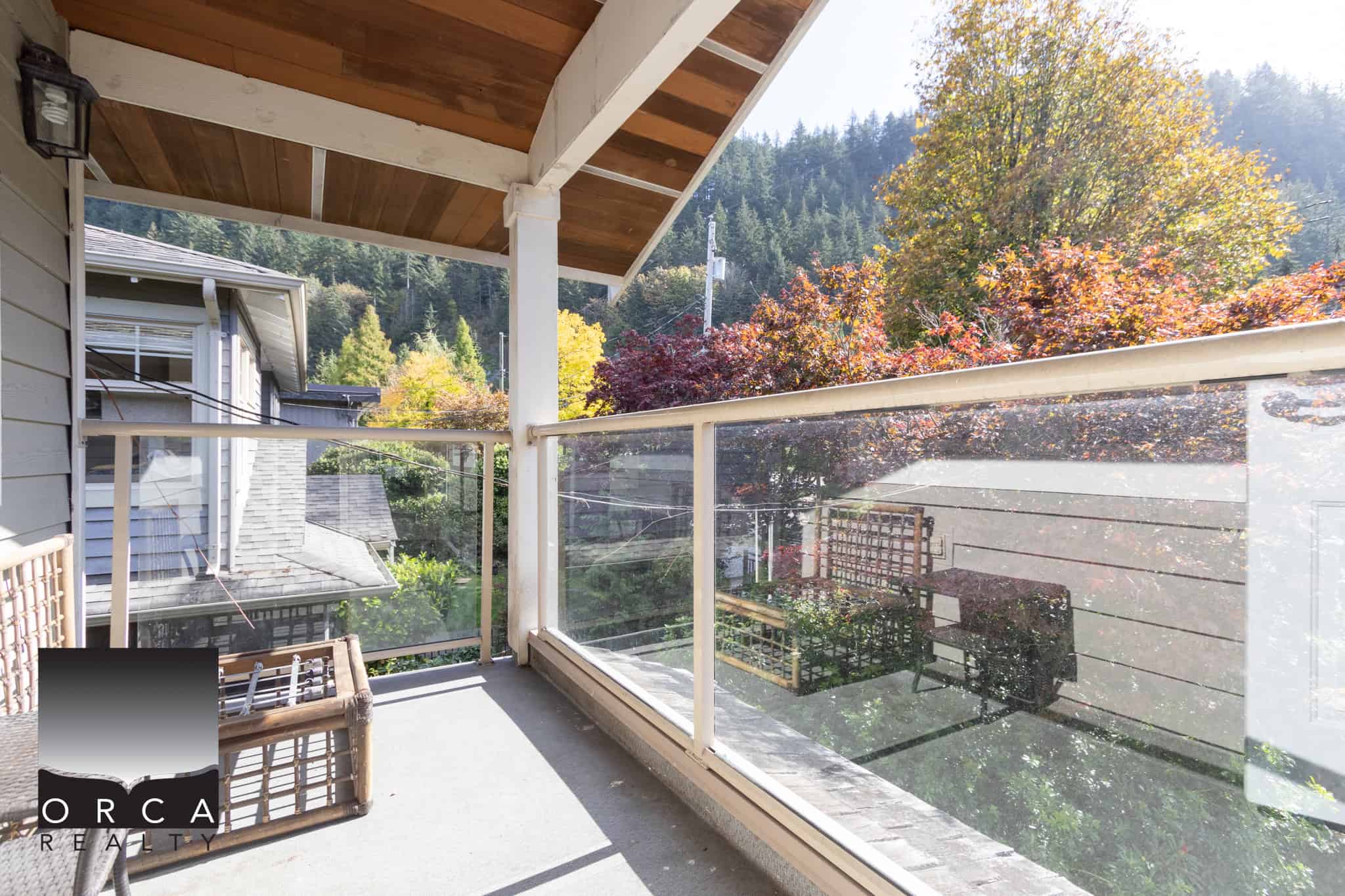 19 Spacious balcony with glass railing overlooking scenic autumn trees and mountain landscape, perfect for relaxing or outdoor dining in a Vancouver area home.