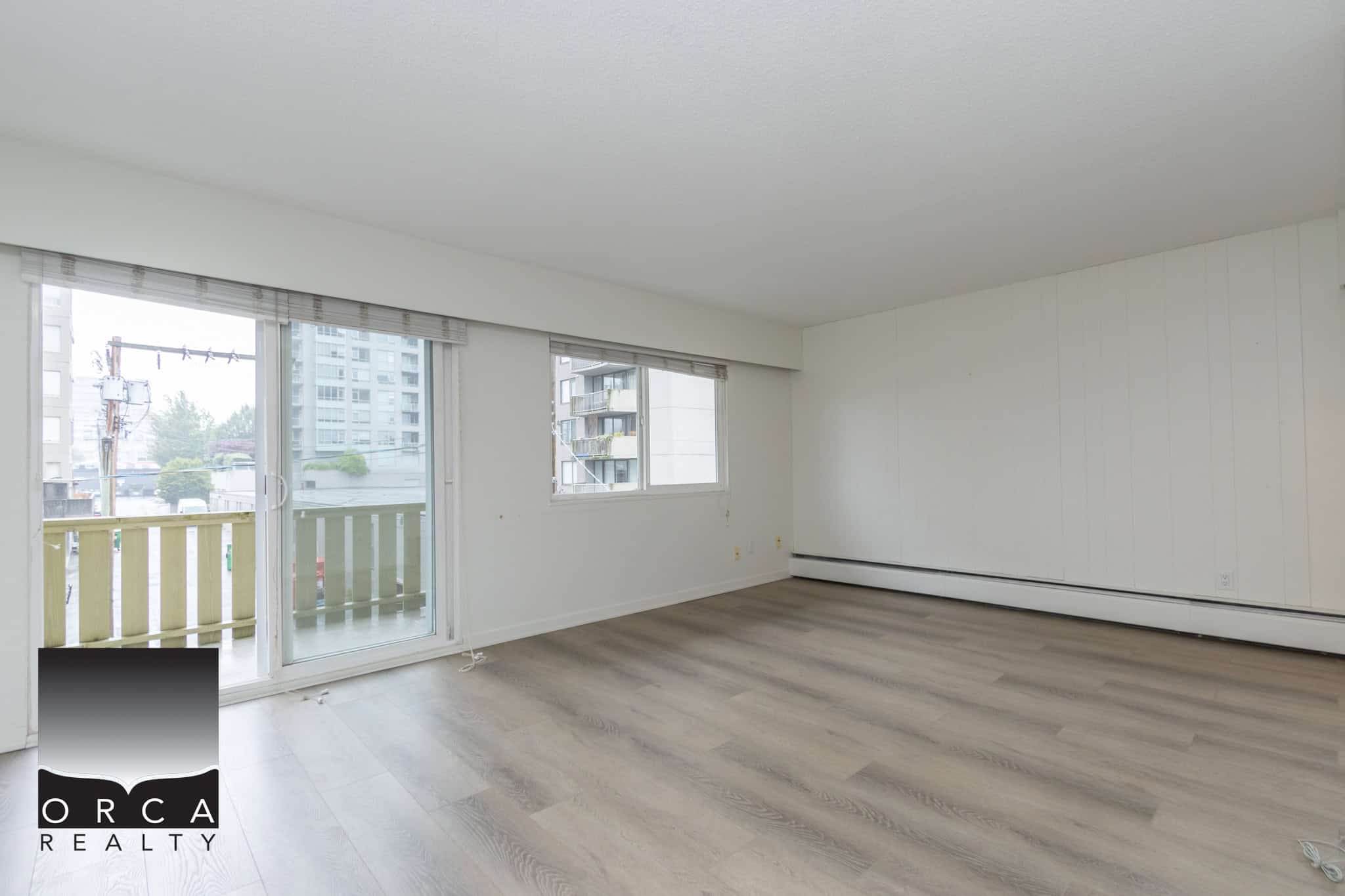 Bright spacious living area with large windows and balcony access, ideal for Vancouver real estate buyers seeking modern apartments with natural light and city views.