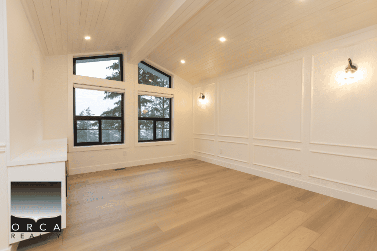 Bright empty living room with large windows, white walls, and wooden flooring, ideal for showcasing Vancouver area real estate listings.