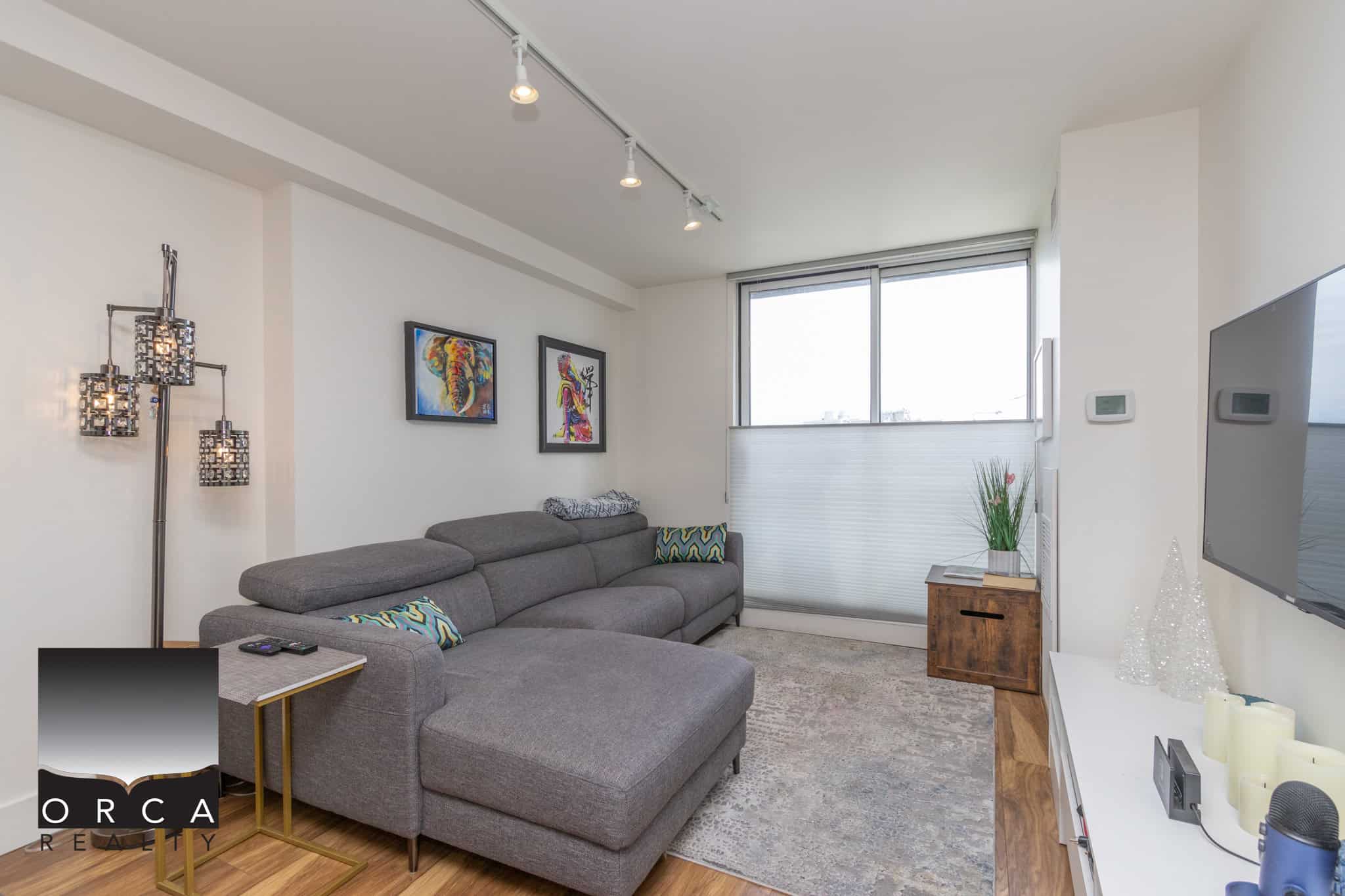 2 Bright modern living room with large window, stylish artwork, and cozy grey sectional sofa, ideal for Vancouver real estate and condo listings.