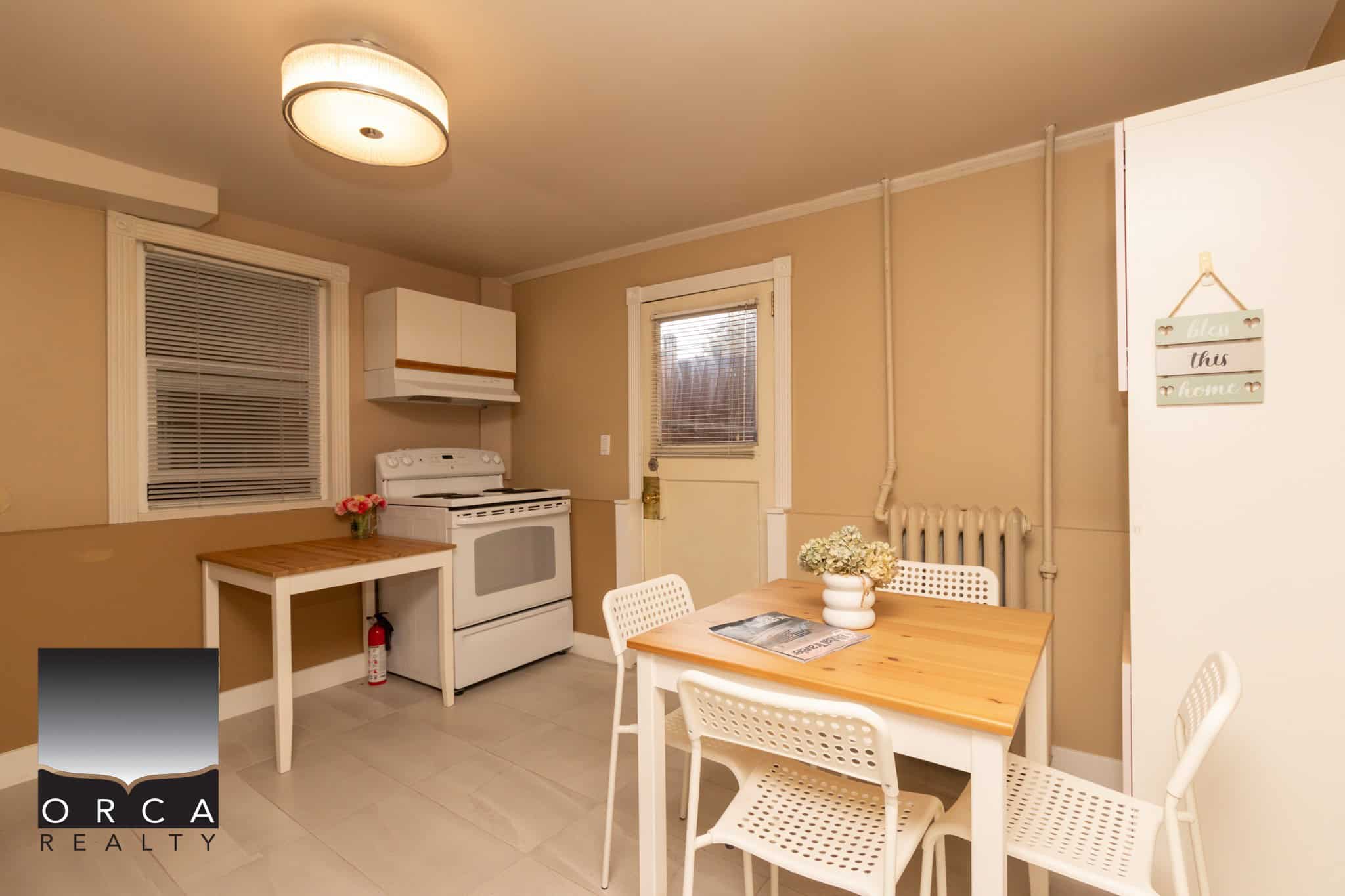 Cozy kitchen and dining area in a Vancouver Island home, featuring white appliances, wooden dining table, and modern decor, ideal for authentic real estate listings.