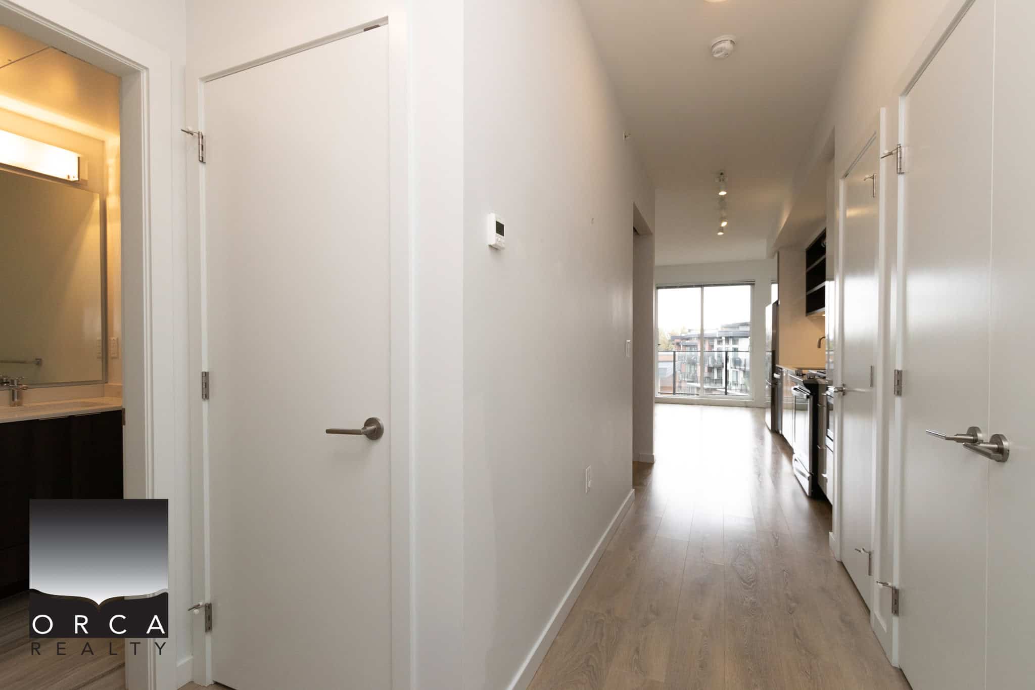 Bright modern condo interior with open layout, white walls, hardwood flooring, and large windows, showcasing contemporary Vancouver-style living space.