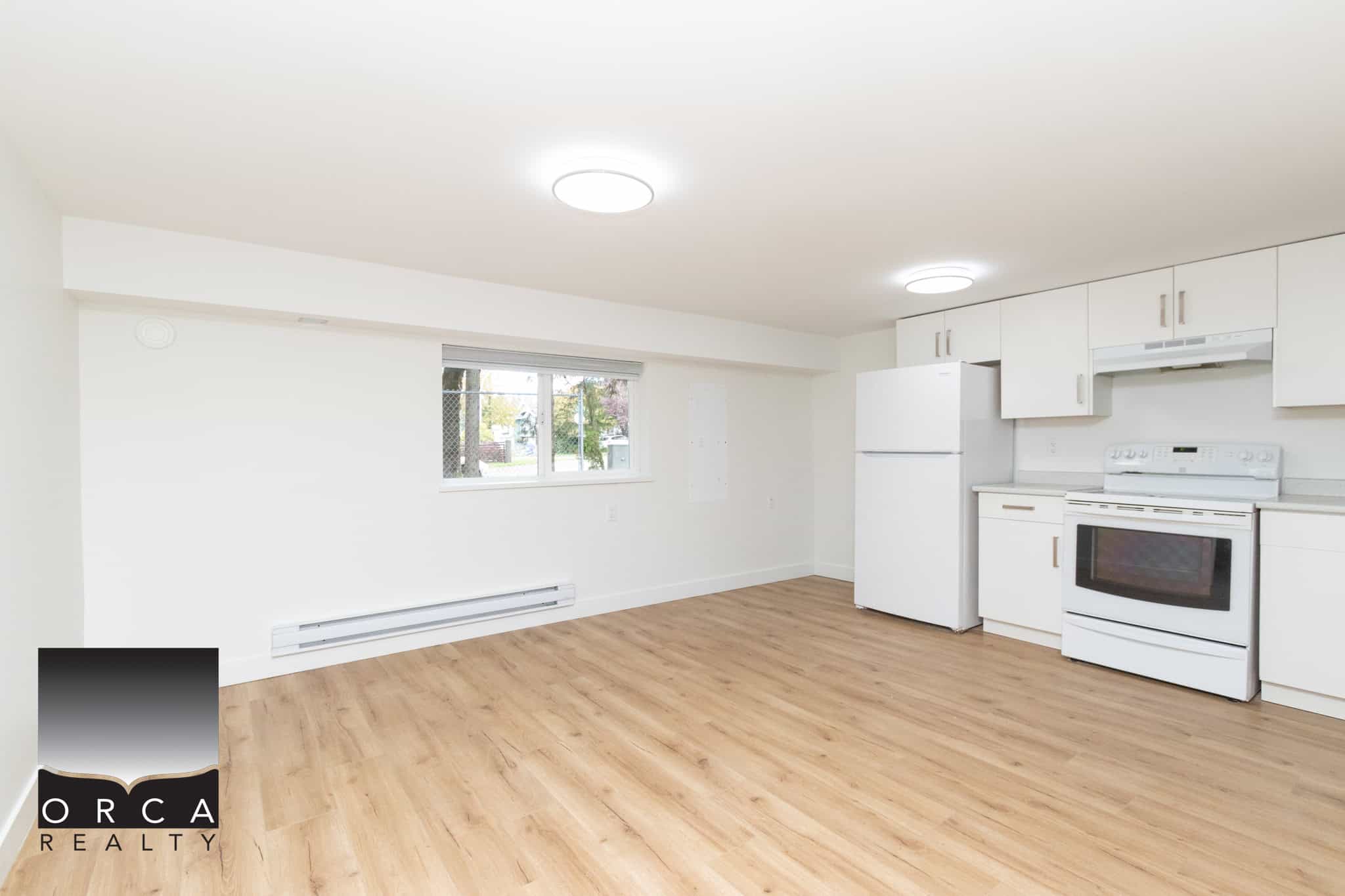 Bright and spacious kitchen with modern white cabinets, white appliances, and laminate flooring, perfect for Vancouver Island real estate buyers seeking a comfortable home.