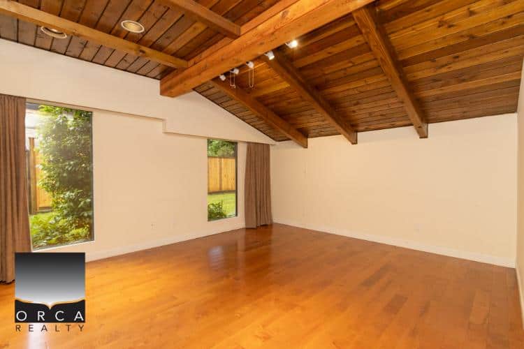 Spacious living room with vaulted wooden ceiling, large windows, and hardwood flooring, perfect for modern homes in Victoria, BC.