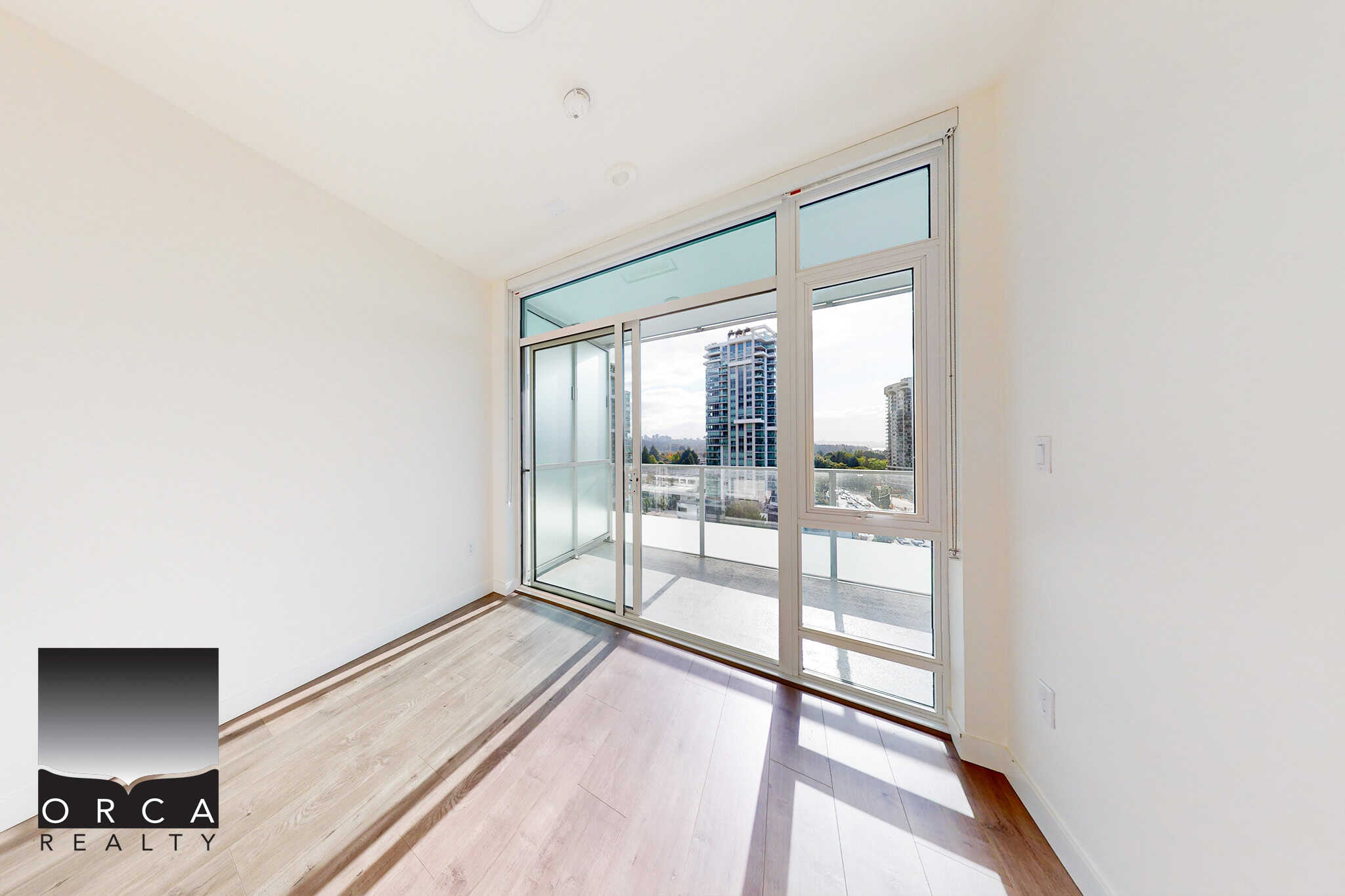 Bright modern condo bedroom with large sliding glass door opening to balcony, showcasing city skyline views in Vancouver, BC. Perfect for urban living and real estate investments.