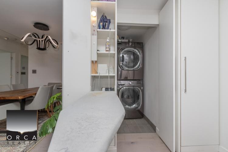 Stacked washer and dryer in a modern laundry area with storage shelves and white cabinetry, ideal for home convenience and utility.