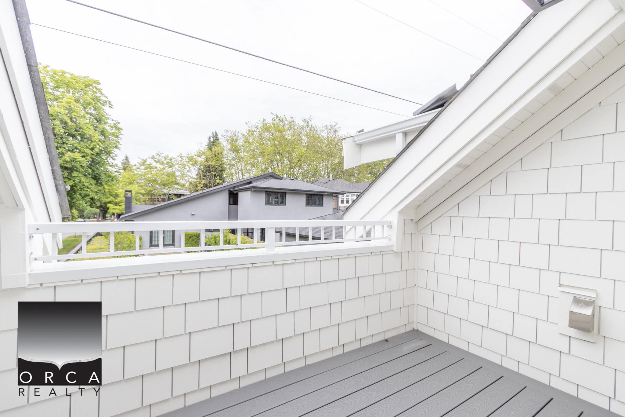 Bright white balcony with modern siding, overlooking a scenic residential neighborhood, perfect for relaxing outdoors in a Vancouver Coastal area property listed by Orca Realty Inc.