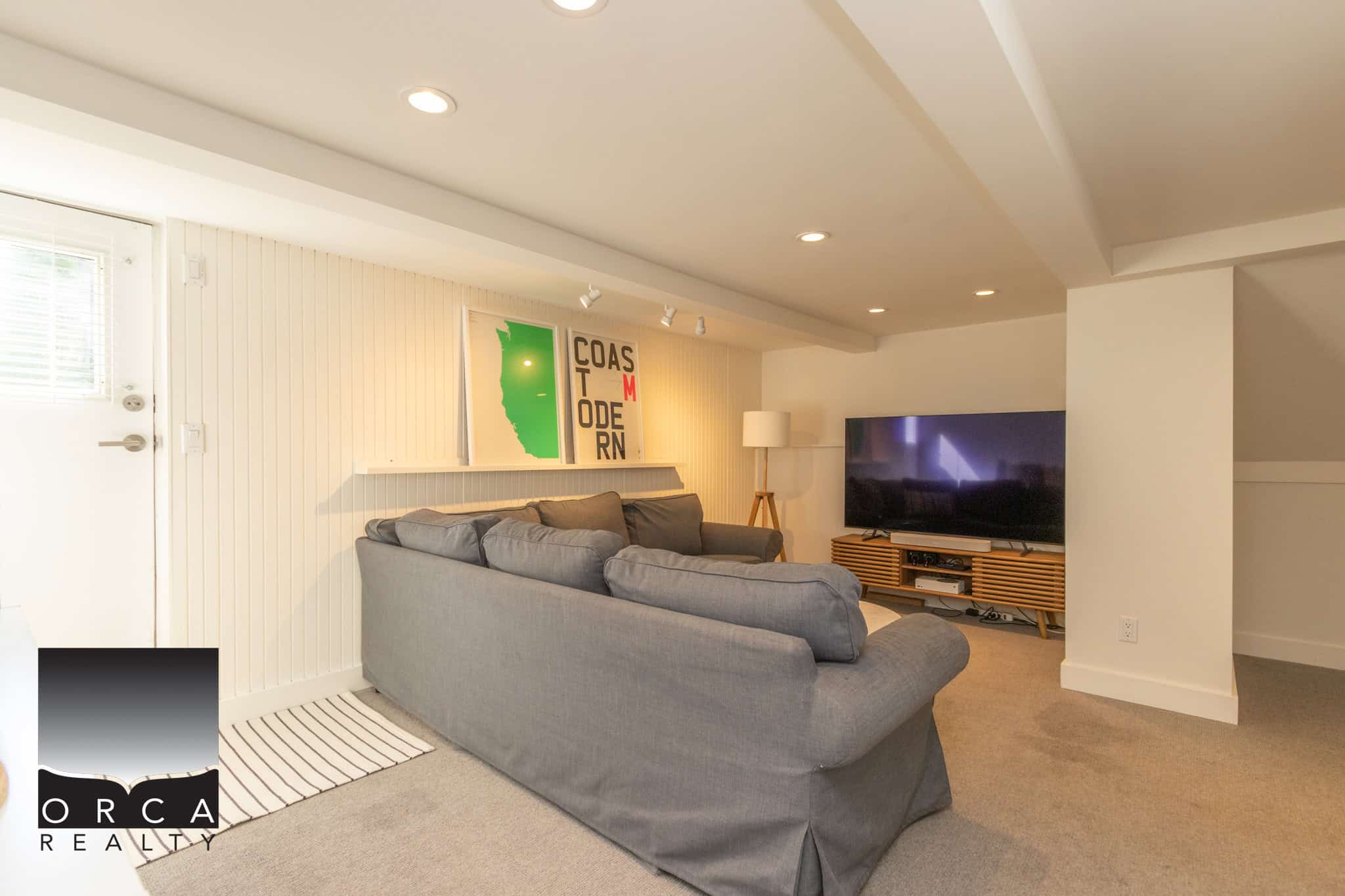 21 Cozy living room with modern decor, large flat-screen TV, neutral tones, and stylish artwork, perfect for relaxing in a Vancouver-area home listed by Orca Realty Inc.