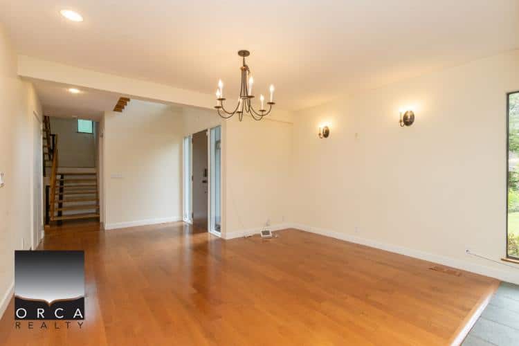 Spacious living room with hardwood floors, modern lighting, and large windows, ideal for Vancouver real estate buyers seeking stylish, family-friendly homes.