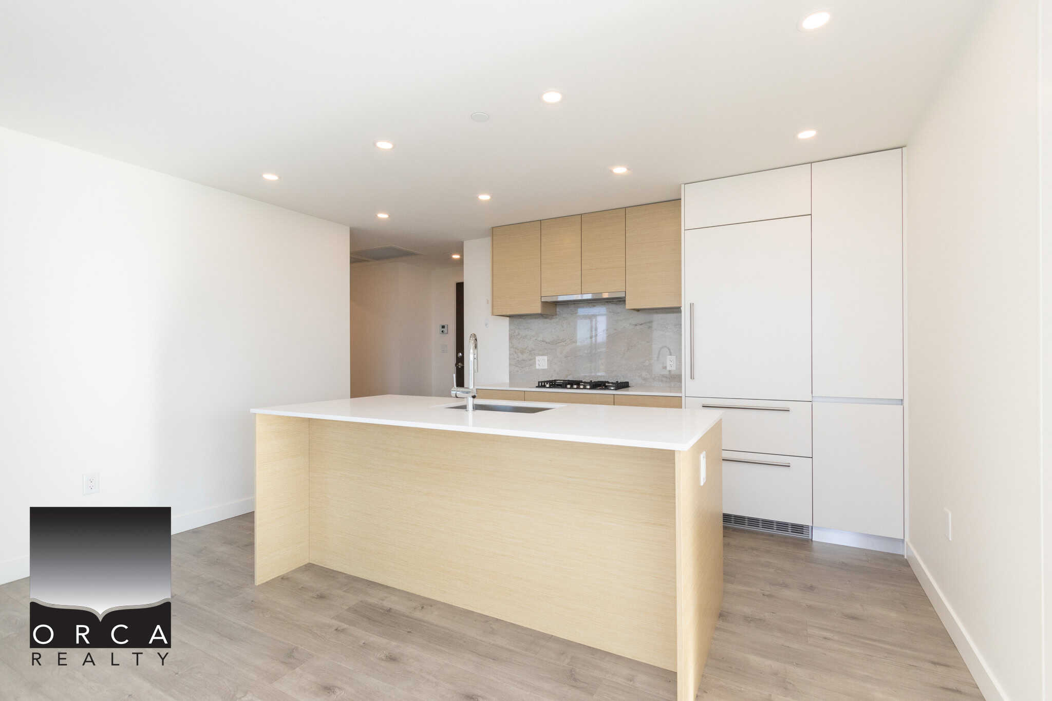 Modern minimalist kitchen with light wood cabinetry, white quartz countertops, and integrated appliances, offering a sleek and functional space perfect for condo living in Vancouver.