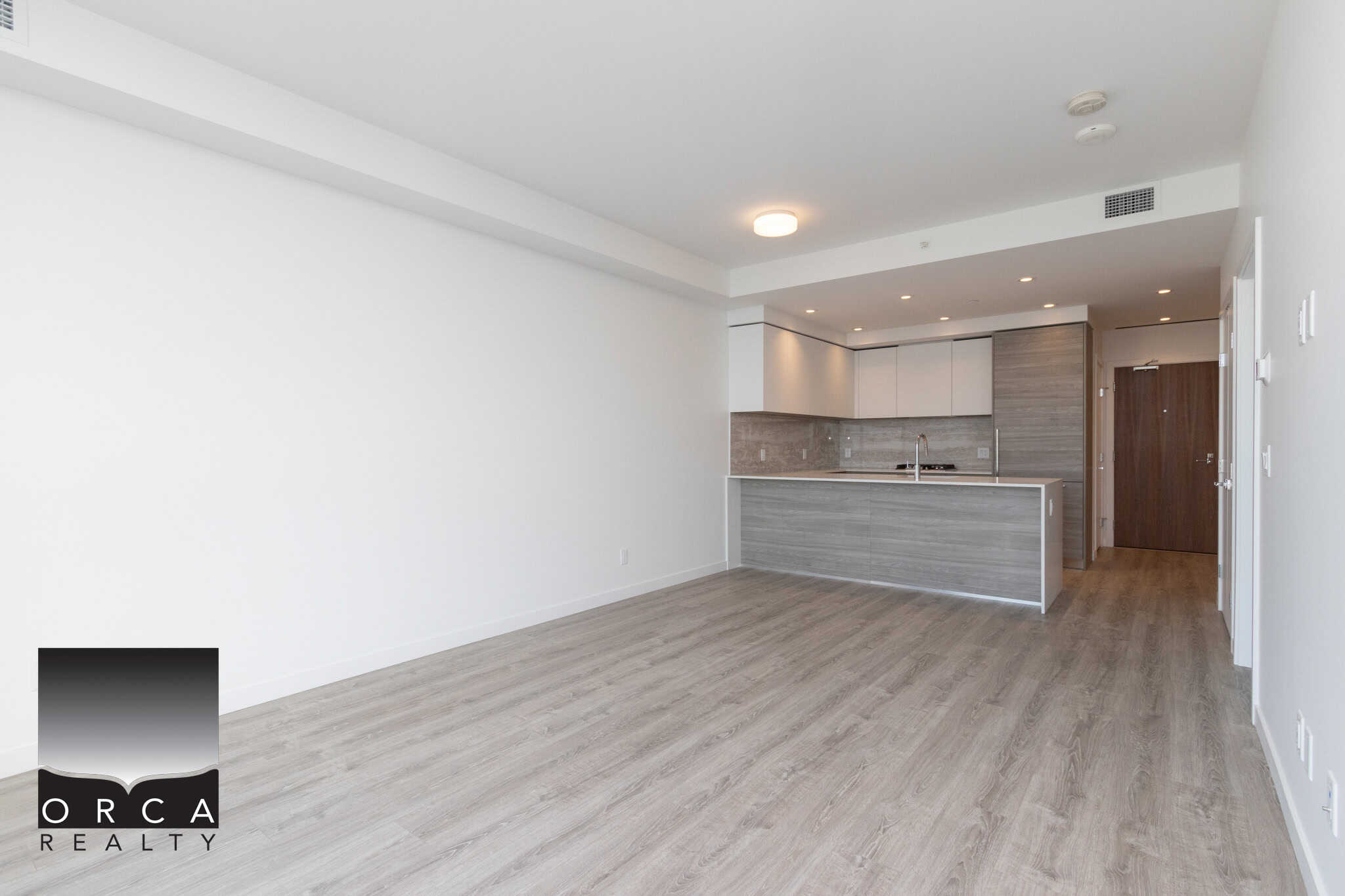 21 Bright, modern open-concept apartment with a sleek kitchen featuring grey wood-style cabinetry, white accents, and stainless steel appliances, ideal for urban living in Vancouver.