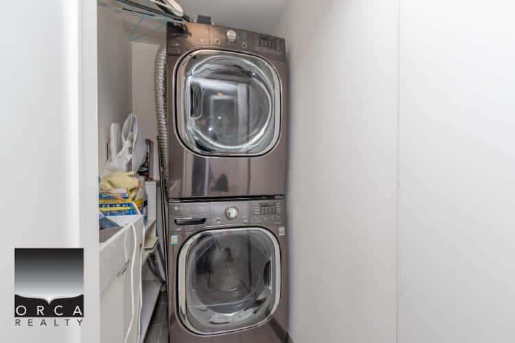 High-quality image of a modern stacked washer and dryer in a compact laundry area, showcasing clean and efficient appliances for residential or rental property cleaning.