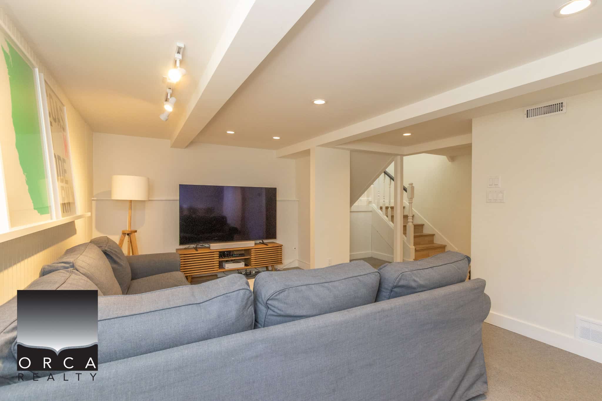 22 Cozy living room with modern decor, grey sofa, flat-screen TV, and warm lighting – perfect for relaxing or entertaining in a scenic Orca Realty Inc. property.
