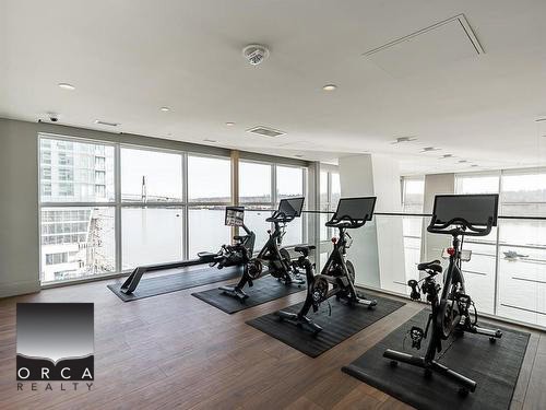 Indoor modern gym with stationary bikes and ventilation, overlooking city skyline through large windows, perfect for fitness in Vancouver.