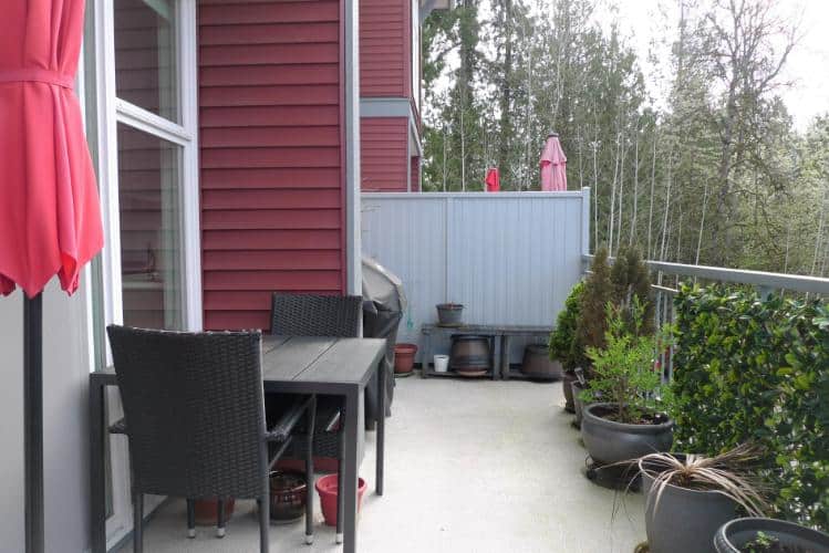 Bright balcony with outdoor furniture, potted plants, and a scenic forest view, perfect for relaxing and enjoying nature in Vancouver's real estate market.