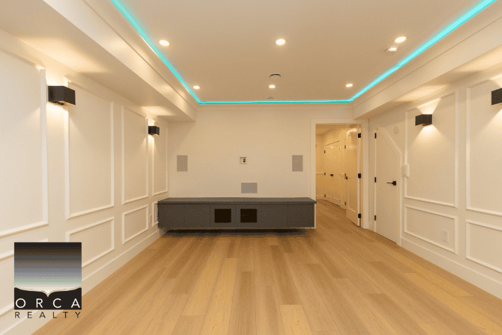 Modern interior living space with elegant wall paneling, ambient lighting, and hardwood flooring showcasing Orca Realty Inc. property listings in BC.