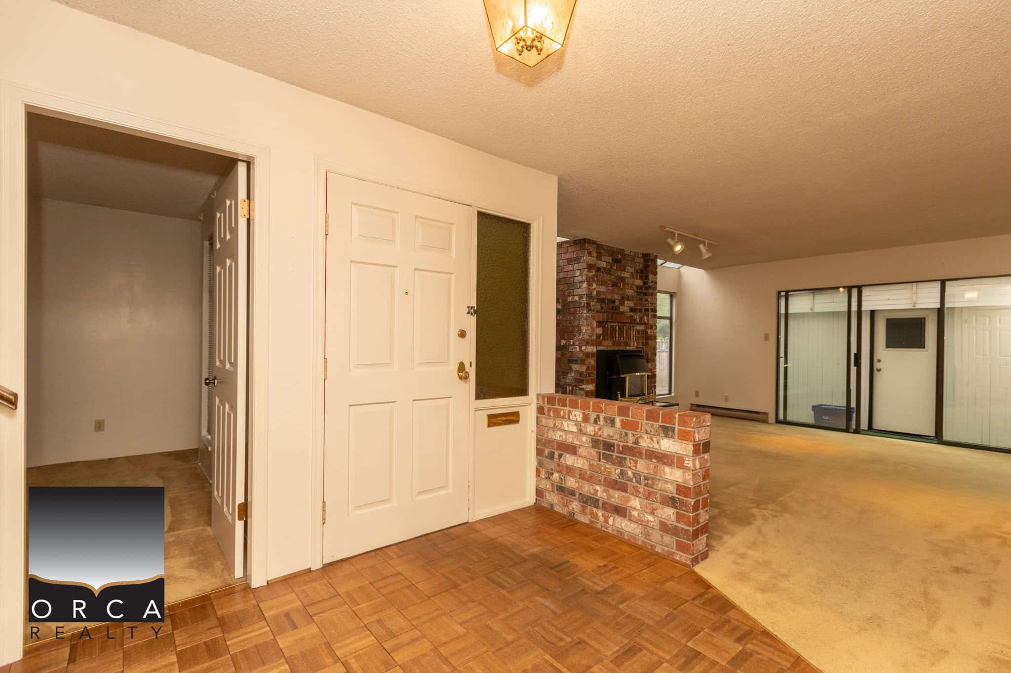 Spacious living room with brick fireplace and sliding glass doors, ideal for Vancouver Island homebuyers seeking comfortable indoor and outdoor spaces.