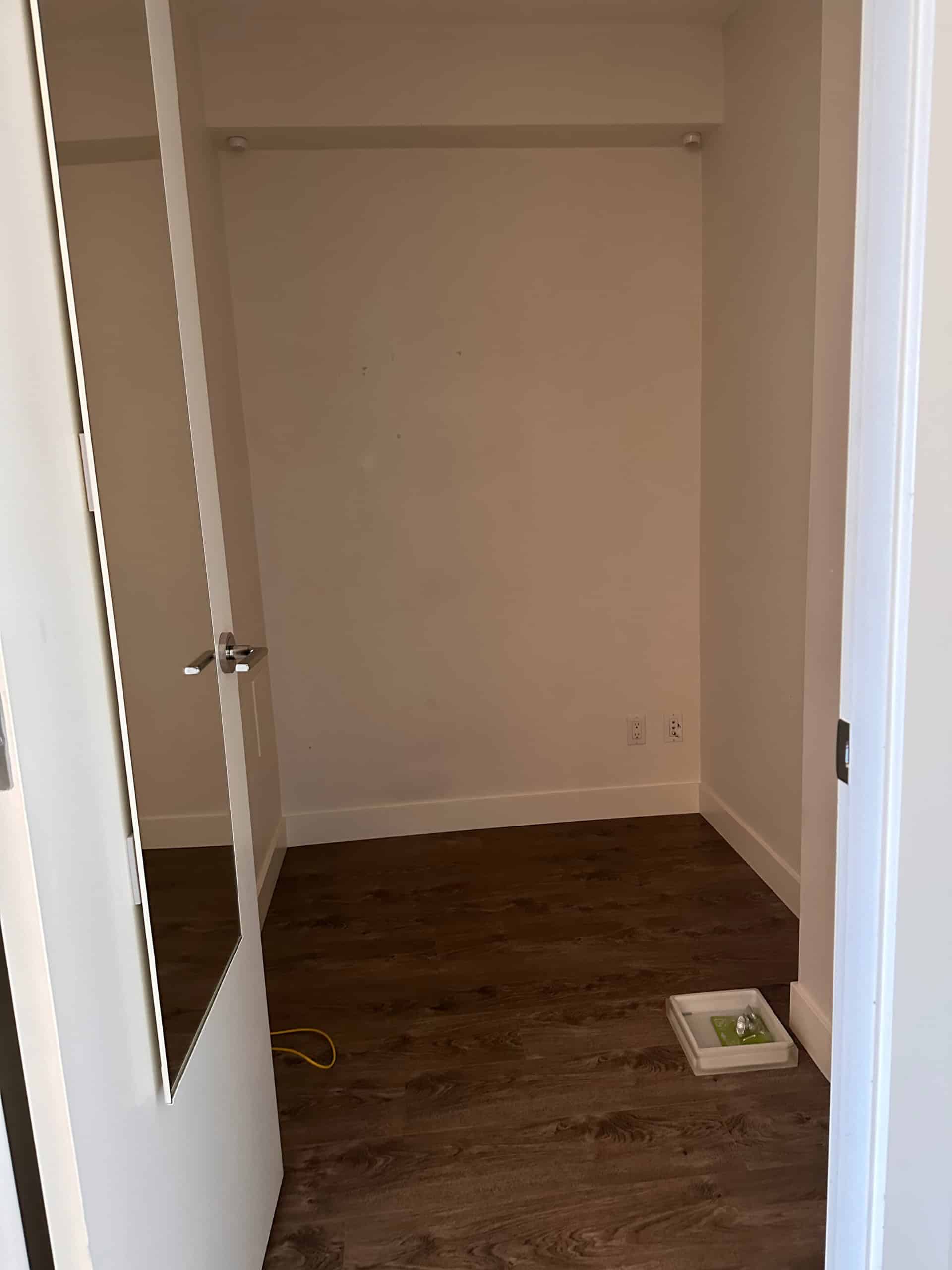 Modern empty closet space in a residential property with white walls, hardwood flooring, and electrical outlets, ideal for a Vancouver home or condo.
