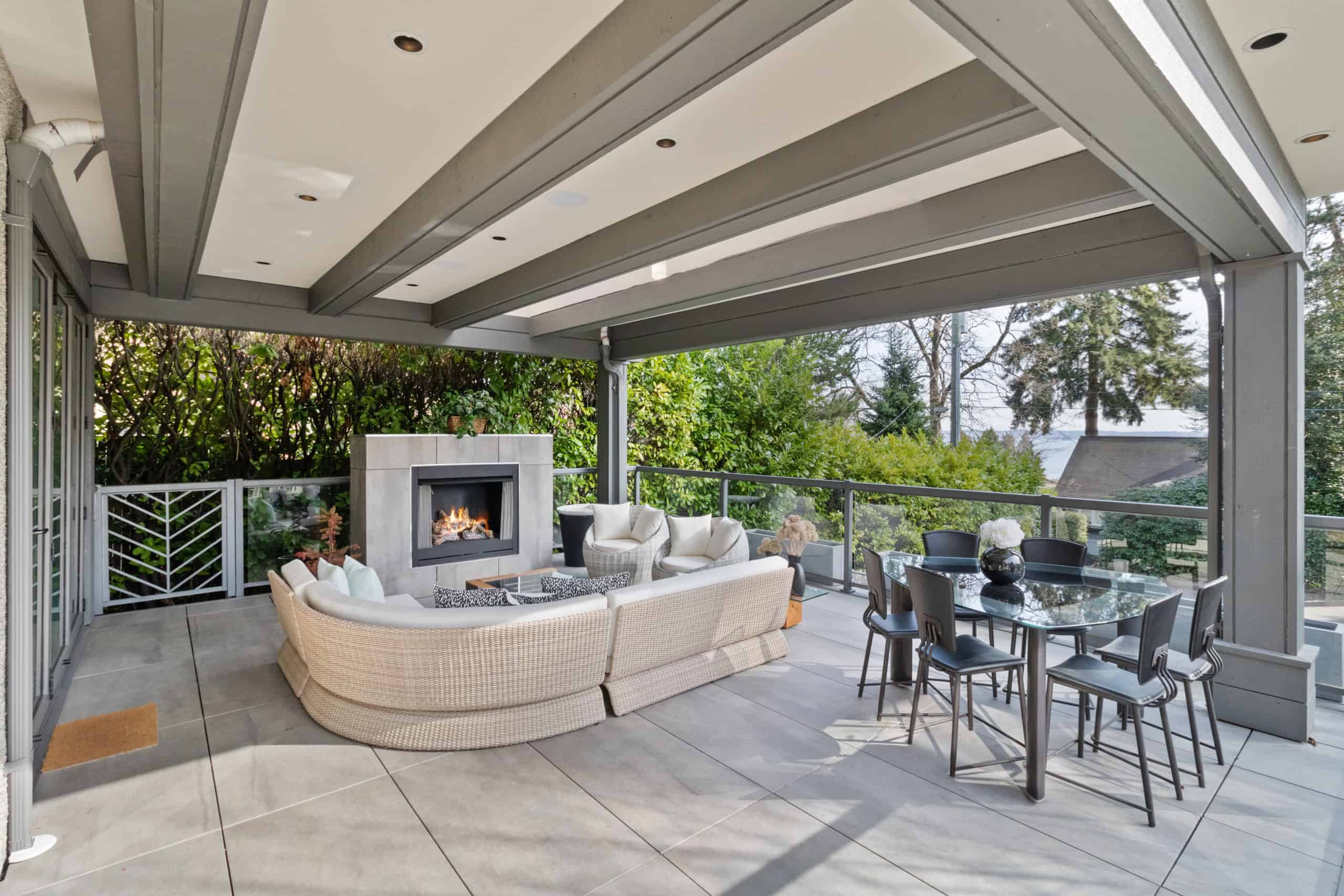 Modern covered outdoor patio with fireplace, stylish seating, and dining area, perfect for outdoor living in Vancouver Island - Orca Realty Inc.