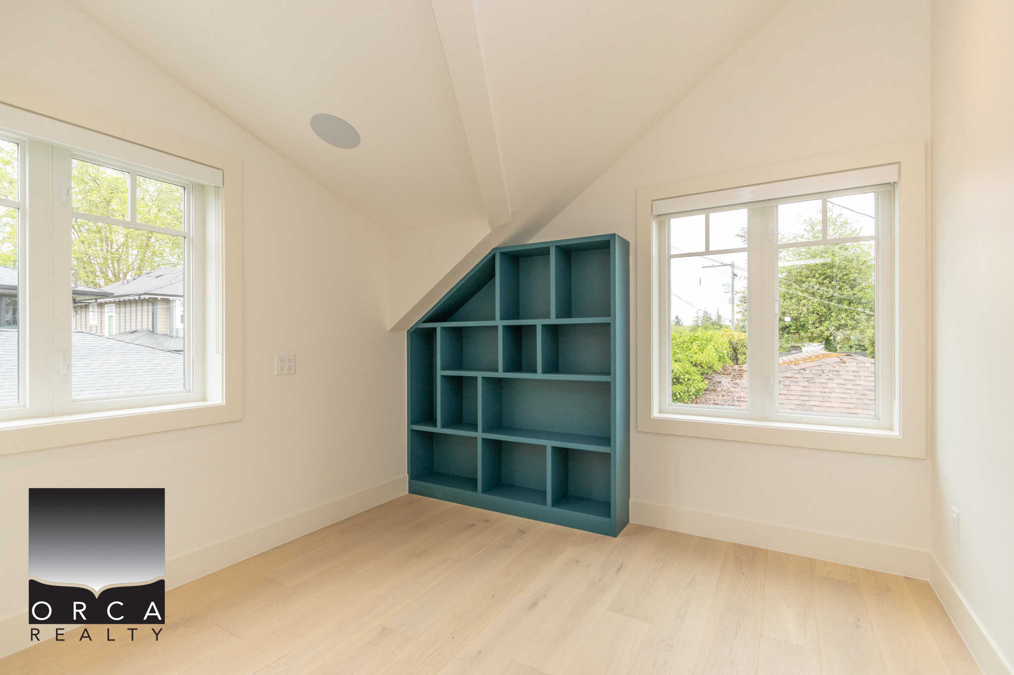 Bright bedrooms with large windows and custom built-in blue shelving units, perfect for storage and organization. The space features light hardwood flooring and natural light, ideal for home comfort and style.
