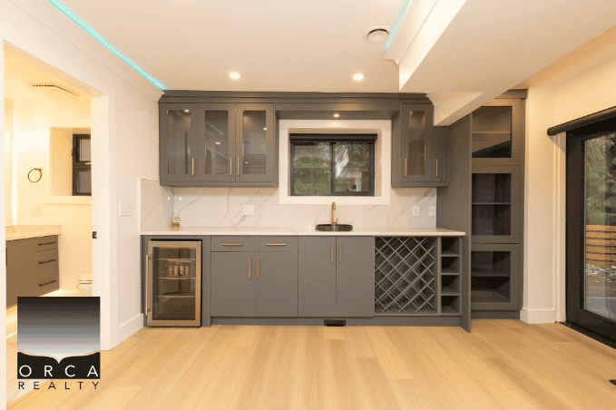 Modern kitchen with grey cabinetry, wine cooler, and wine rack, perfect for Vancouver homebuyers - Orca Realty Inc.