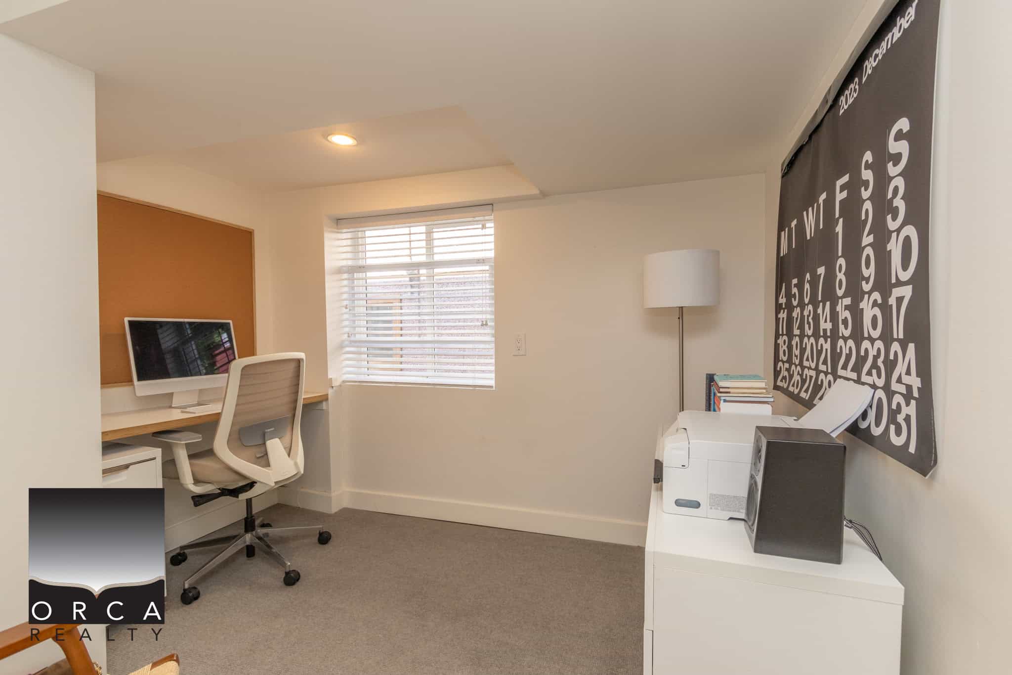 24 Modern home office space with desk, computer, and comfortable ergonomic chair, featuring a large calendar wall and window with blinds, ideal for remote work or study in Vancouver BC.