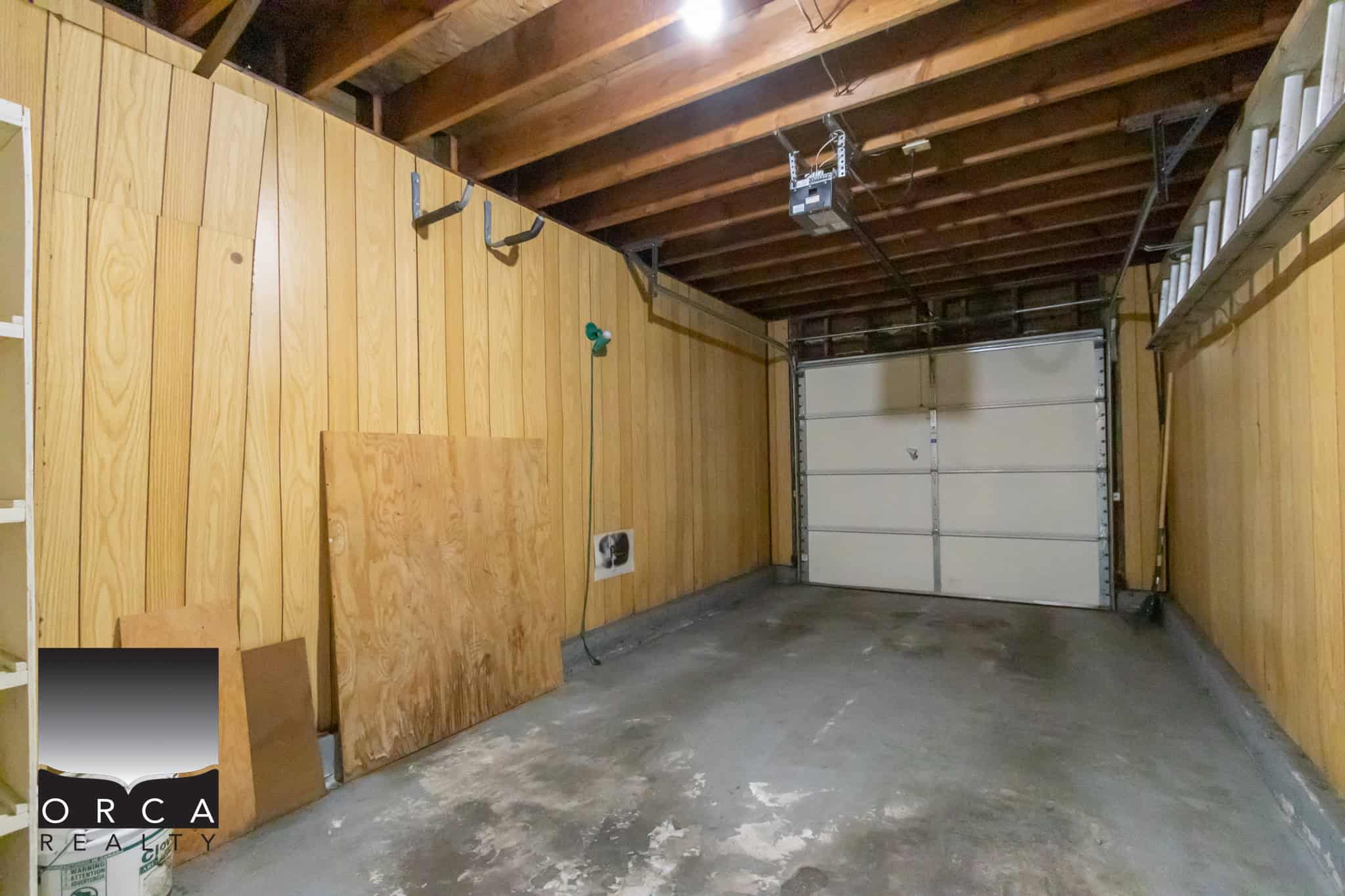 Spacious two-car garage interior with wooden panel walls, concrete floor, and garage door, ideal for storage or parking in Vancouver Island.