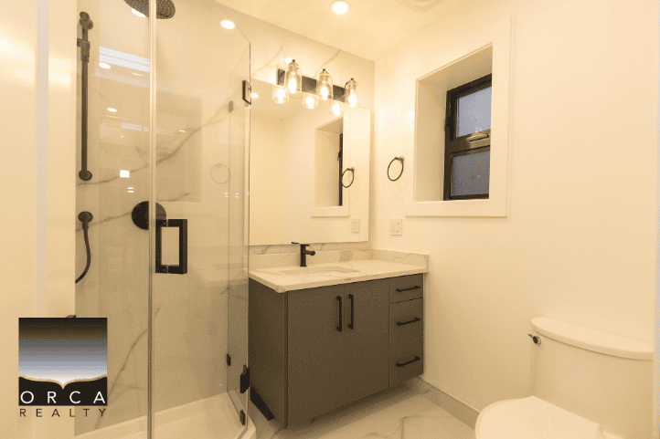 Modern home bathroom with glass-enclosed shower, sleek vanity, and contemporary fixtures, showcasing upscale Vancouver real estate by Orca Realty Inc.