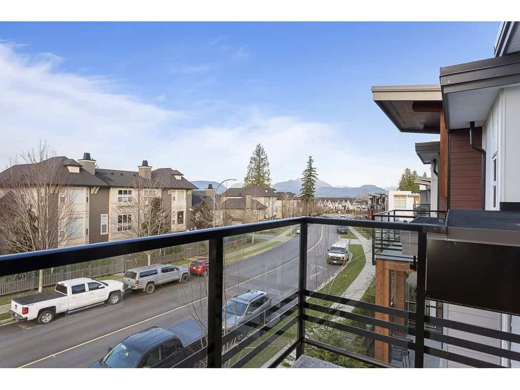Great view from a modern balcony overlooking a peaceful residential street with mountain scenery in the background. Perfect for relaxing or enjoying the outdoors in a vibrant neighbourhood.